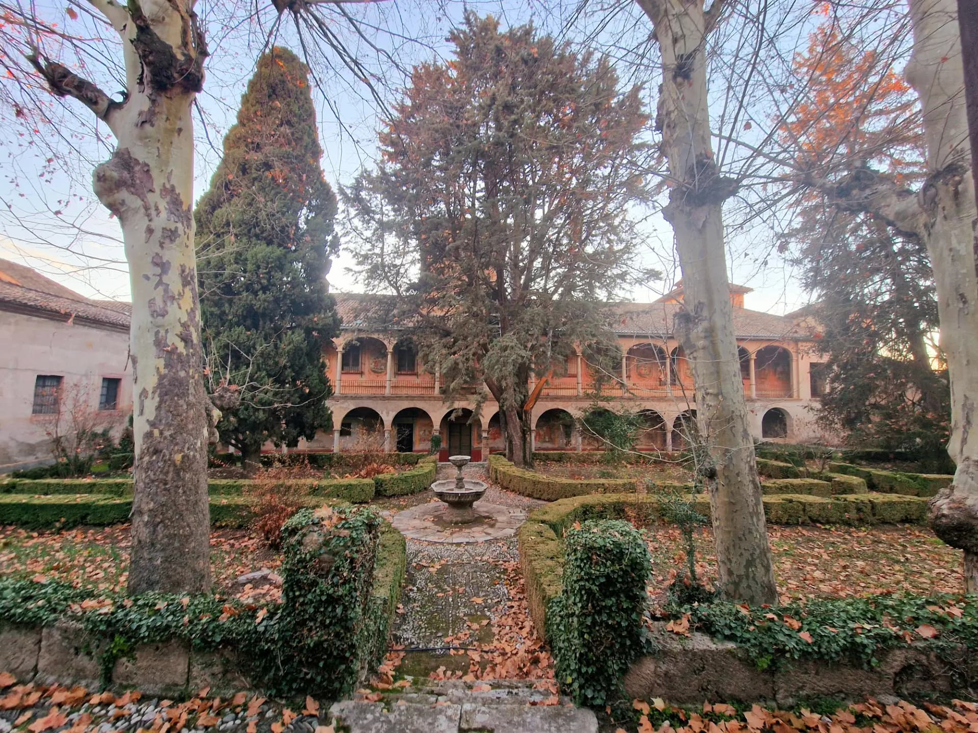 Jardín con fuente y galerías de arcos del Palacio del Cuzco de Víznar, entre árboles de otoño