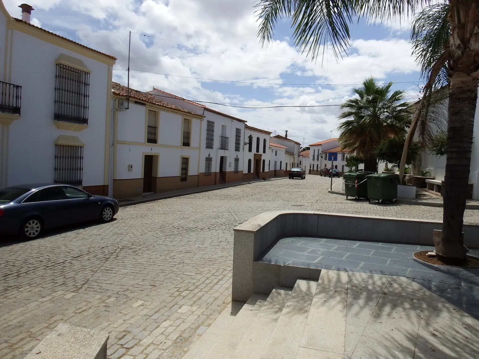 Calle empedrada de Paymogo con casas blancas y palmeras