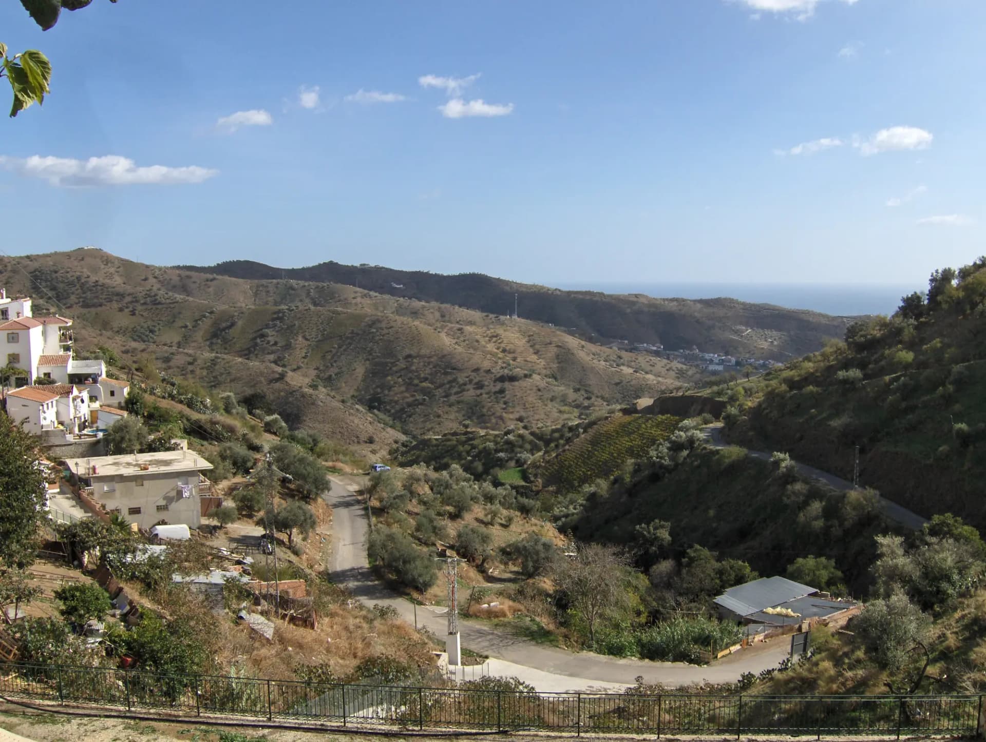 Valle y cerros de Moclinejo con casas al borde de la carretera y el mar al fondo