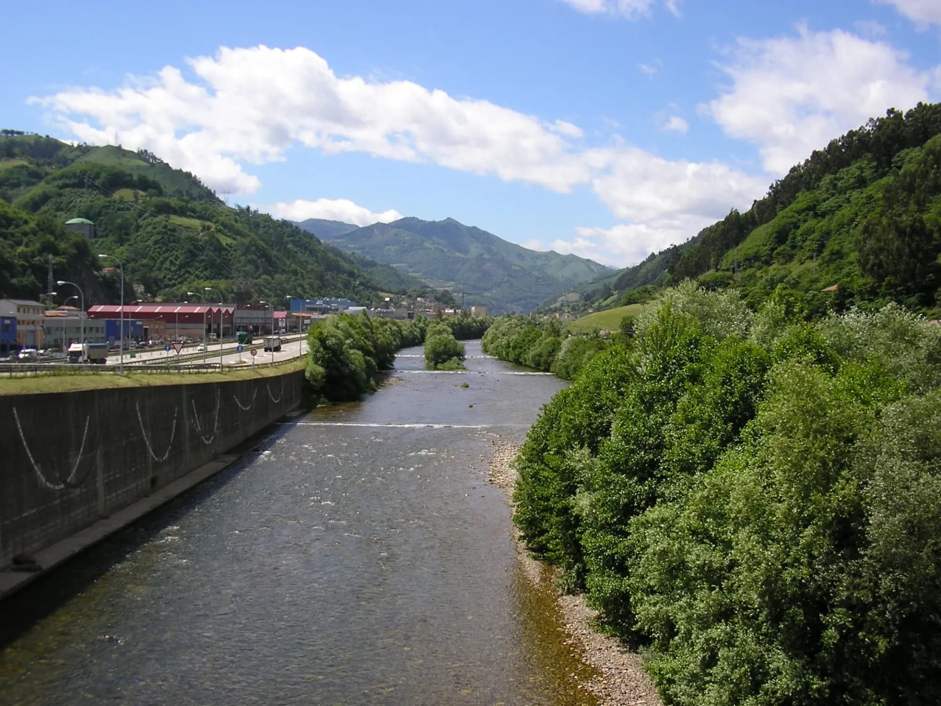 El río Caudal a su paso por Mieres, entre laderas verdes y con la ciudad al fondo