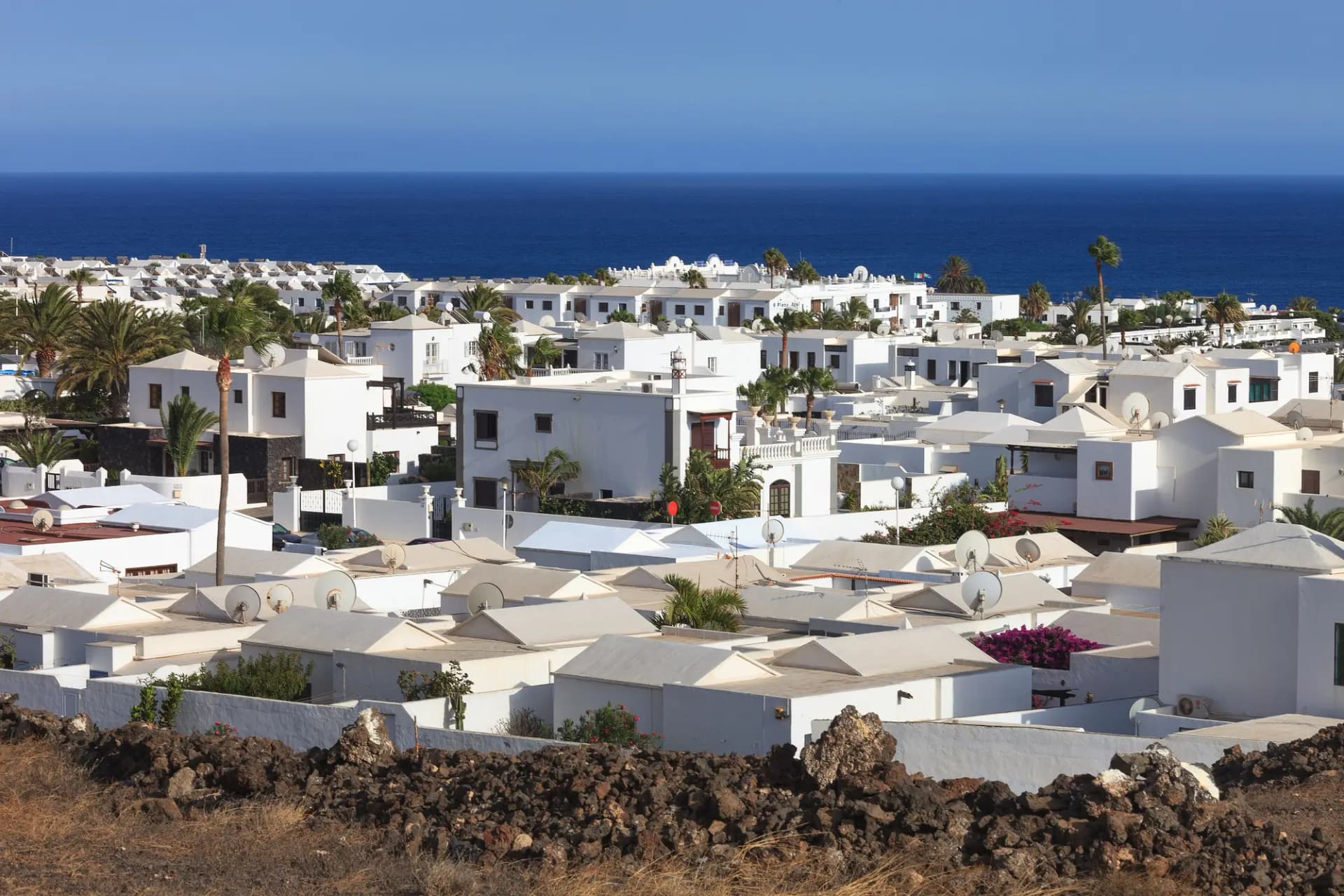 Casas blancas de Puerto del Carmen entre palmeras con el mar al fondo
