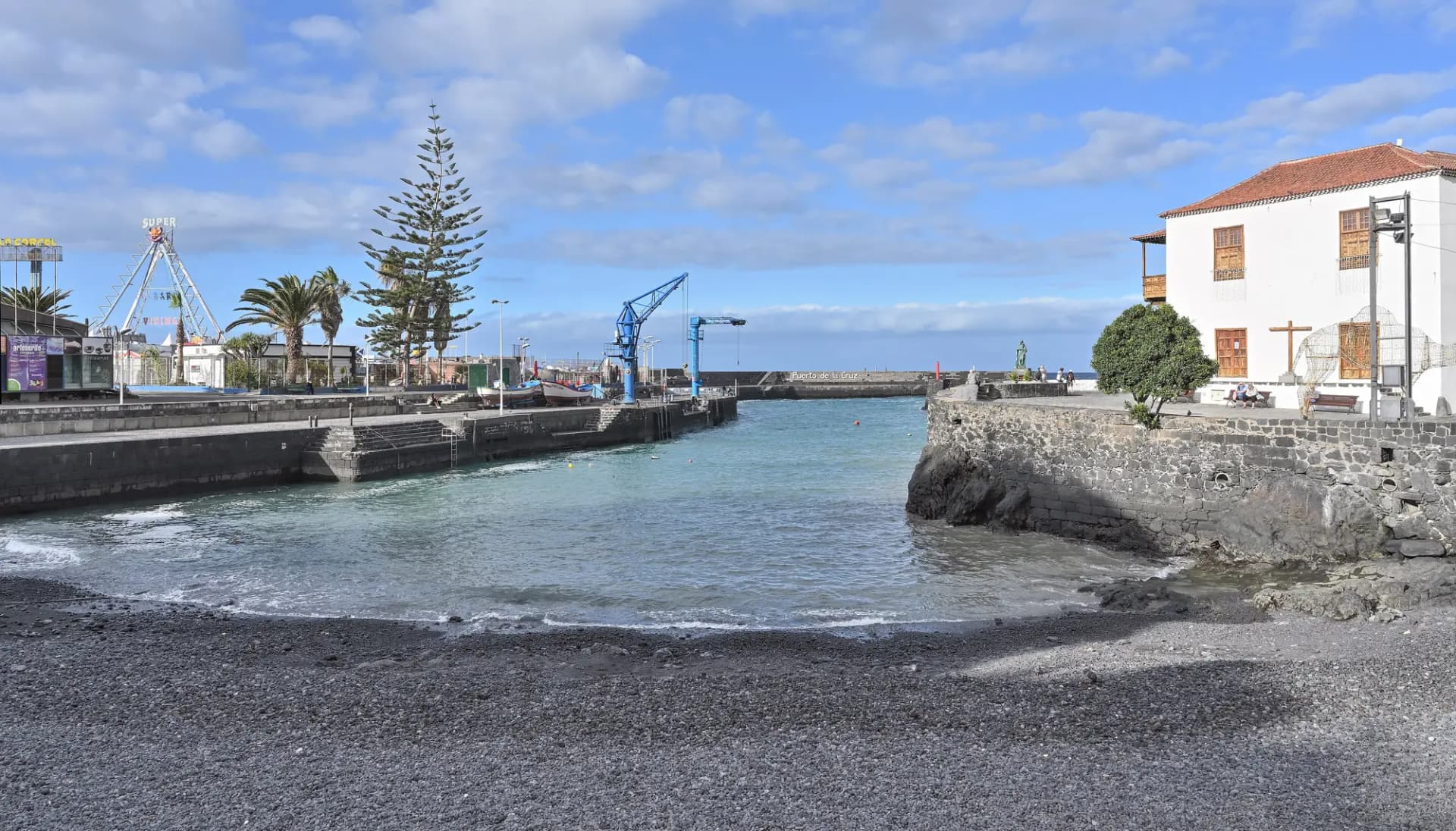 Muelle pesquero de Puerto de la Cruz con su playa de arena negra y casas antiguas junto al agua