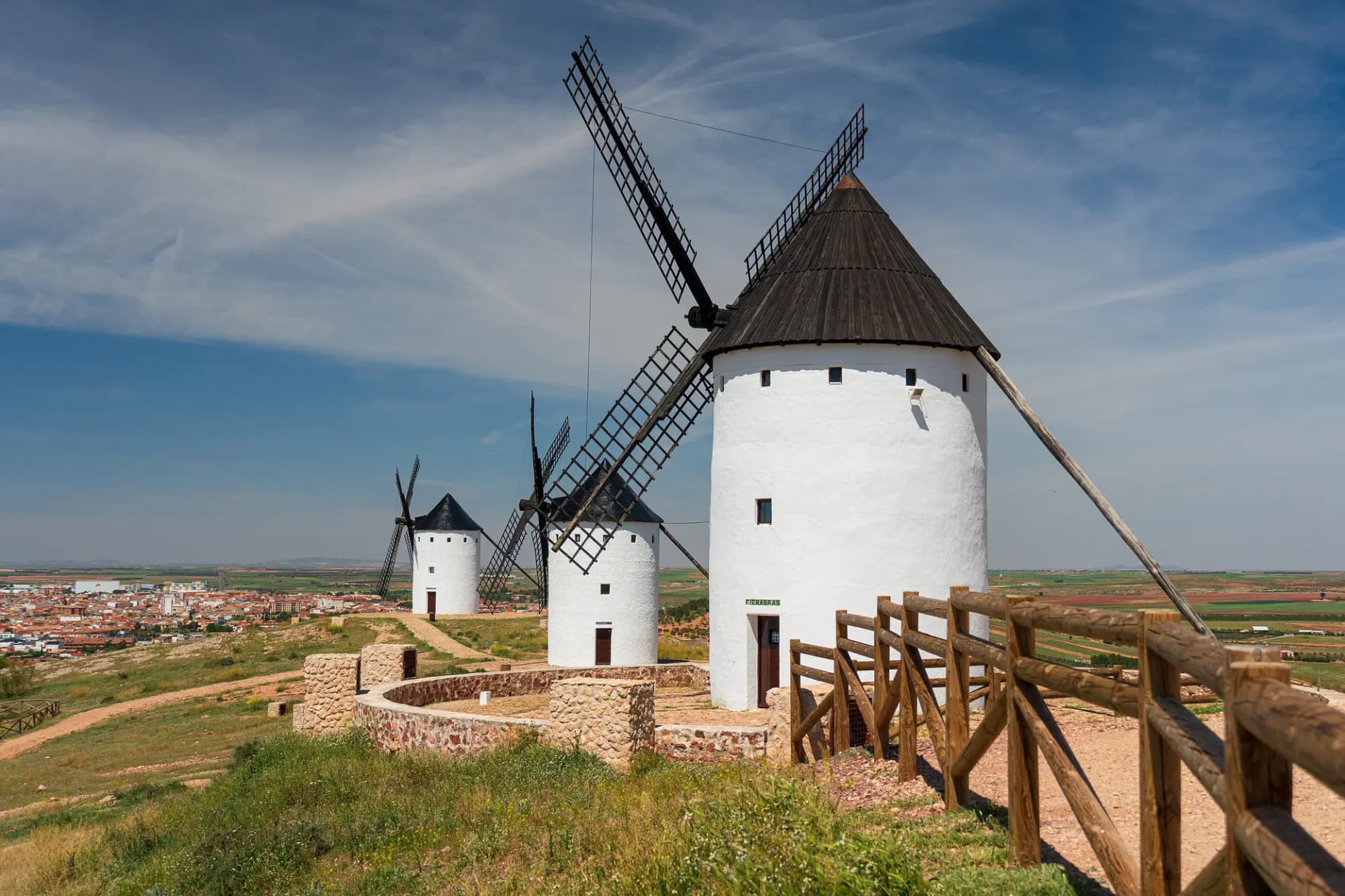 Molinos de viento blancos de Alcázar de San Juan con la llanura manchega y la ciudad al fondo