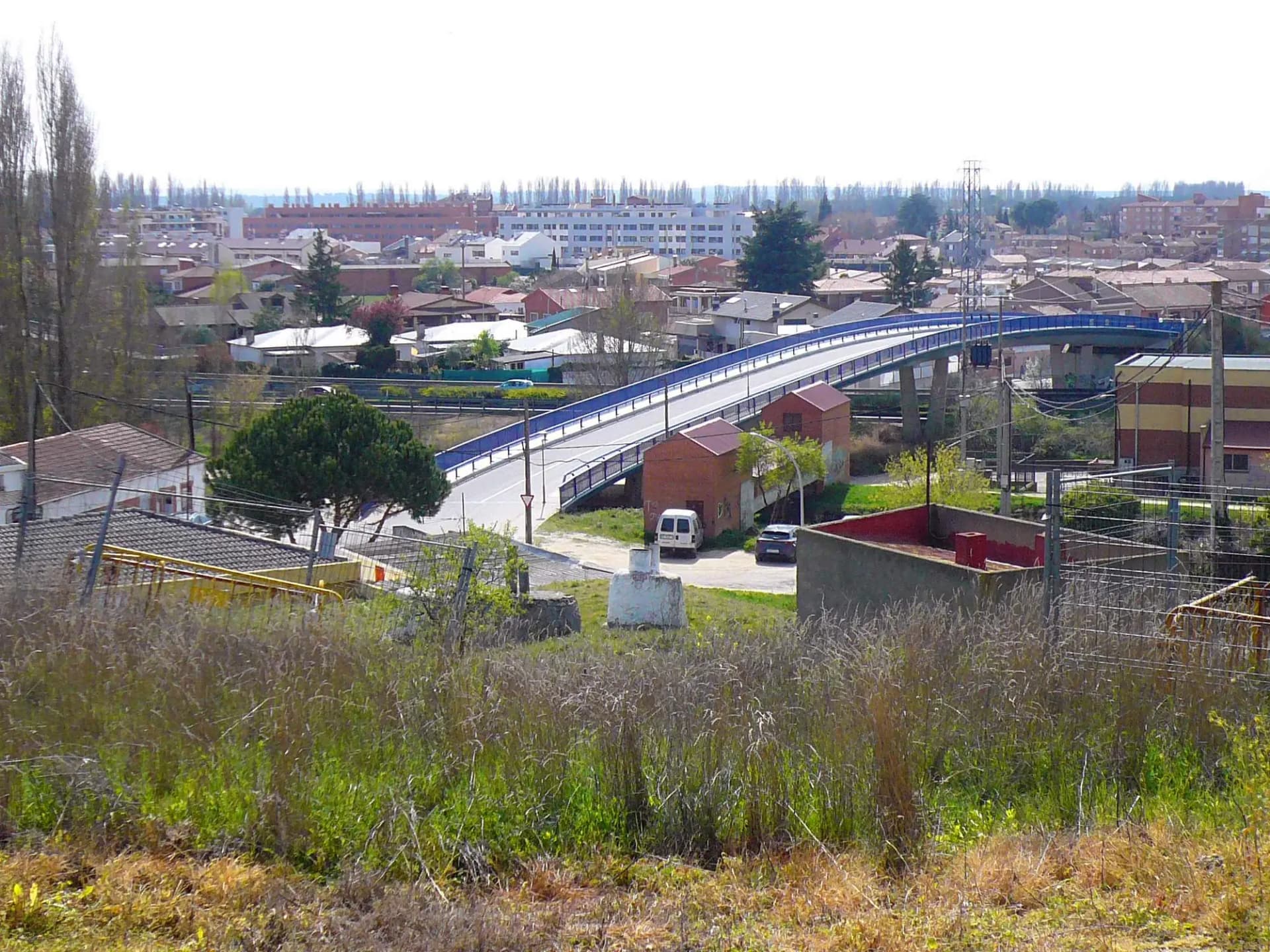 Vista de Laguna de Duero desde la ermita del Villar, con casas bajas, un puente y pinares al fondo