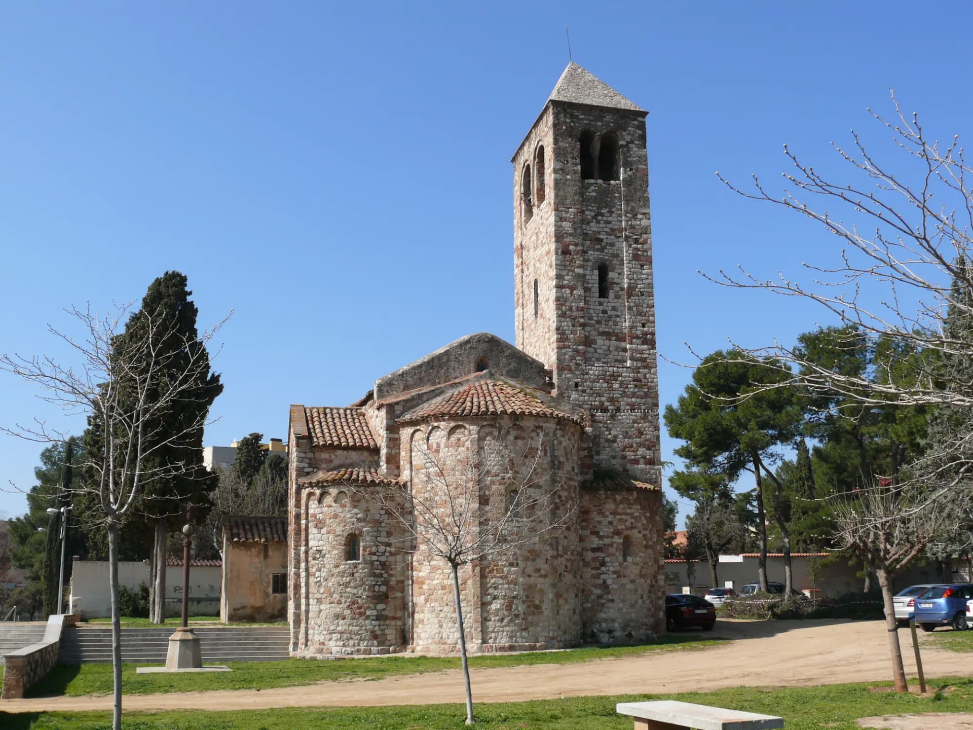 Iglesia románica de Santa Maria de Barberà, con su campanario de piedra y el ábside entre árboles