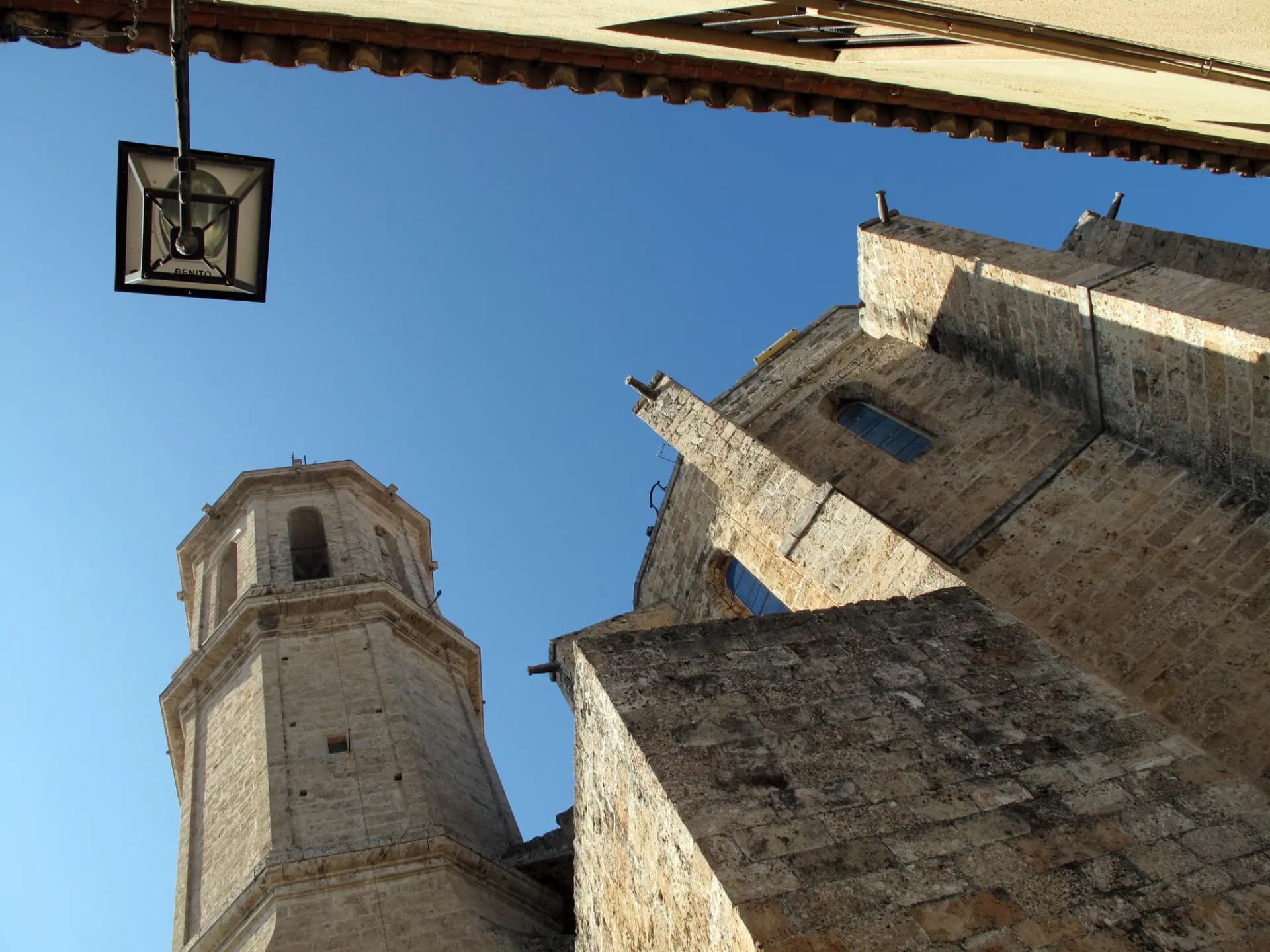 Campanario y ábside de piedra de la iglesia de Santa Eulàlia de Esparreguera bajo un cielo azul