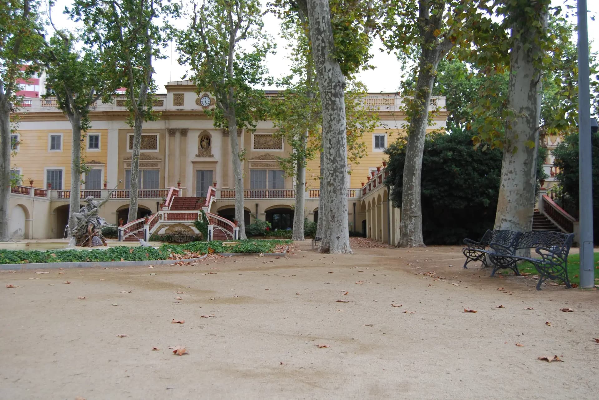Jardín del Palau Falguera de Sant Feliu de Llobregat con plátanos y la fachada del palacio al fondo