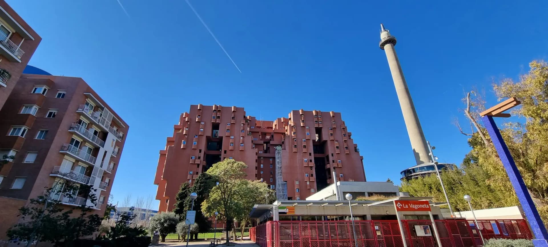 Edificio Walden 7 de color rojo teja junto a la antigua chimenea de la cementera en Sant Just Desvern
