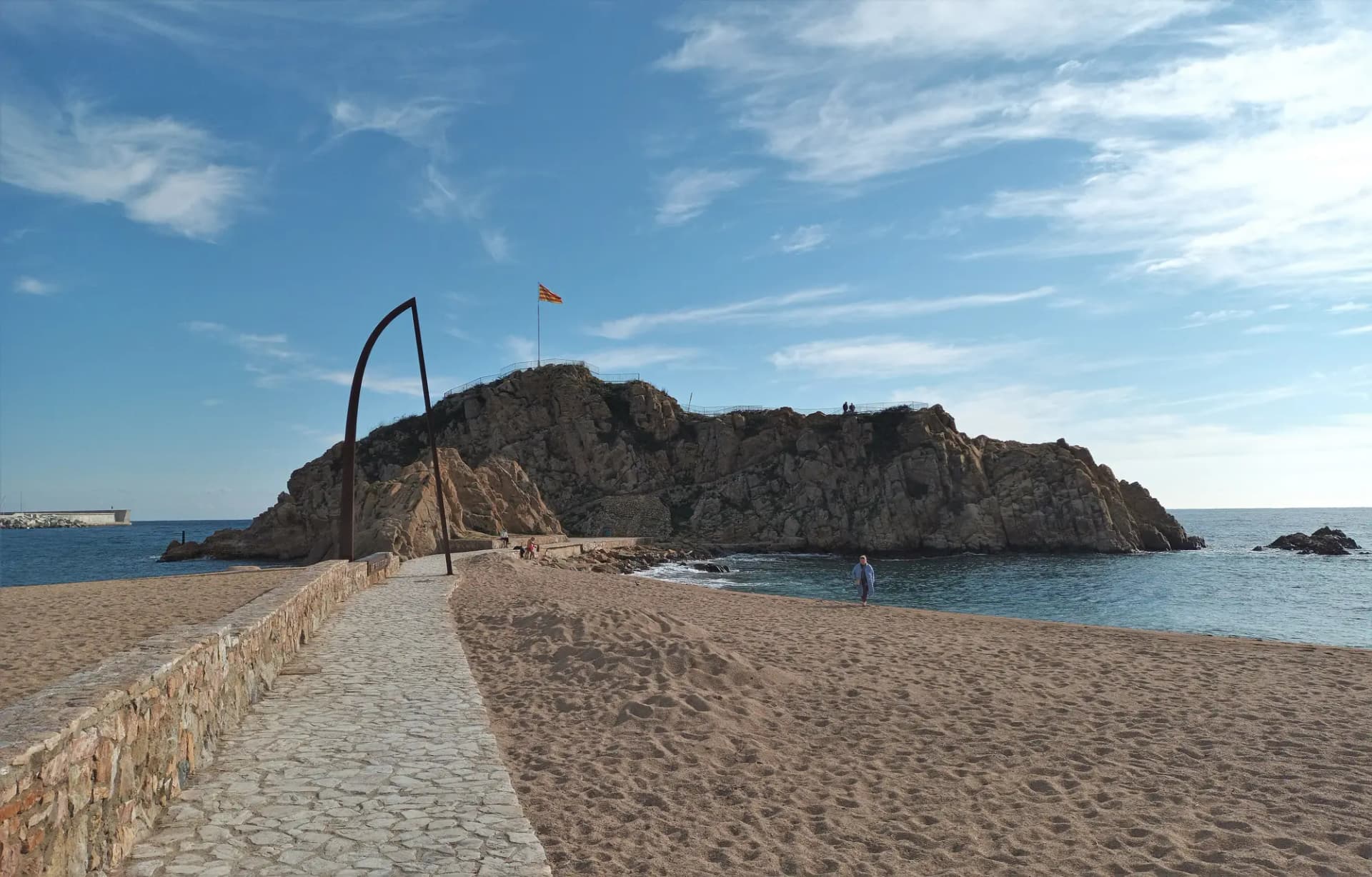 La roca de Sa Palomera en la playa de Blanes, con el paseo de piedra que lleva hasta ella