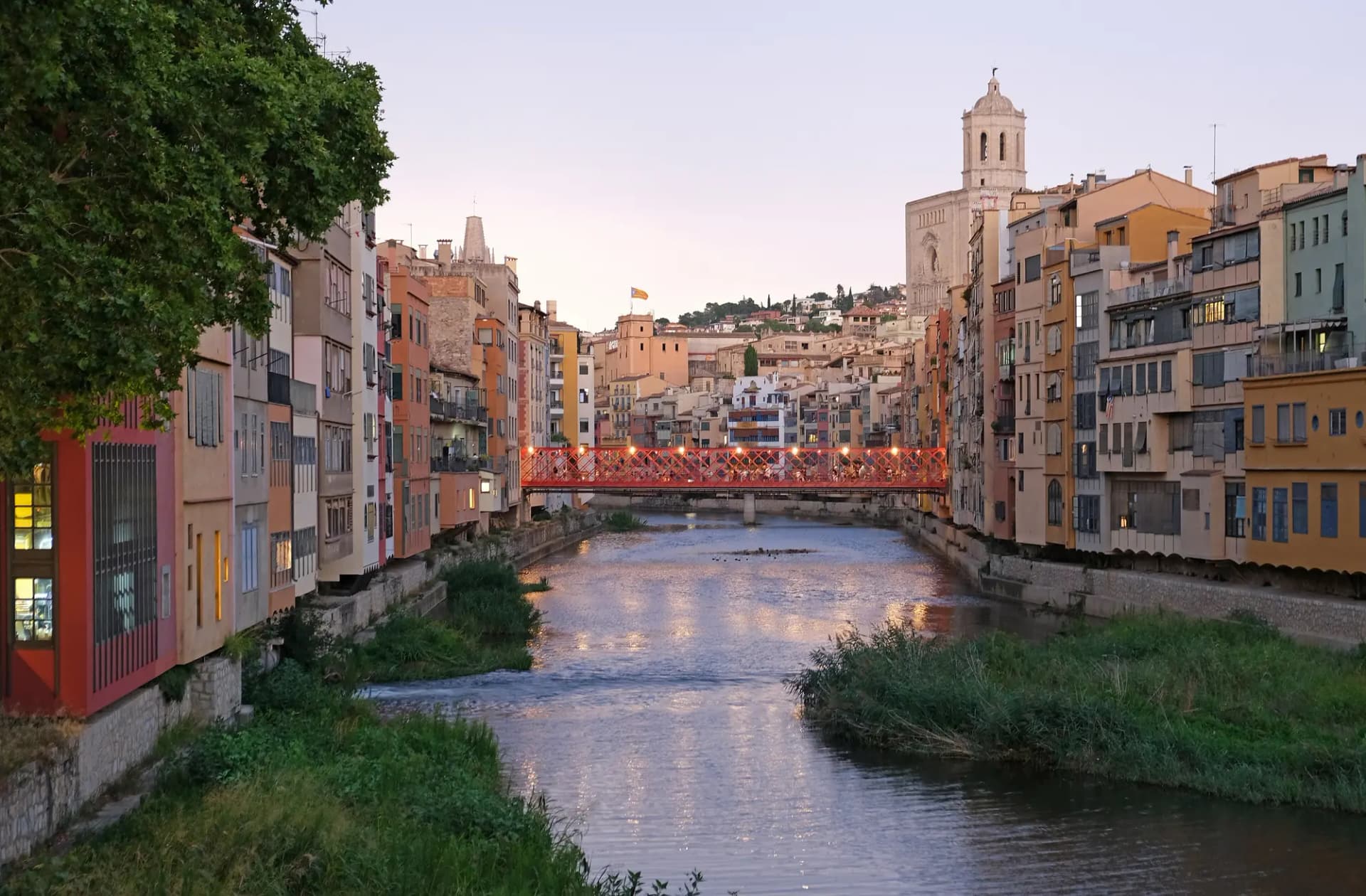 Casas de colores sobre el río Onyar en Girona, con el puente rojo de las Peixateries Velles y el campanario de la Catedral al fondo