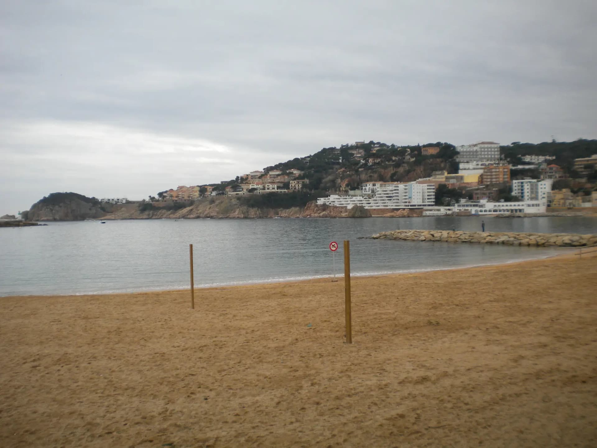 Playa y bahía de Sant Feliu de Guíxols con edificios sobre la colina al fondo