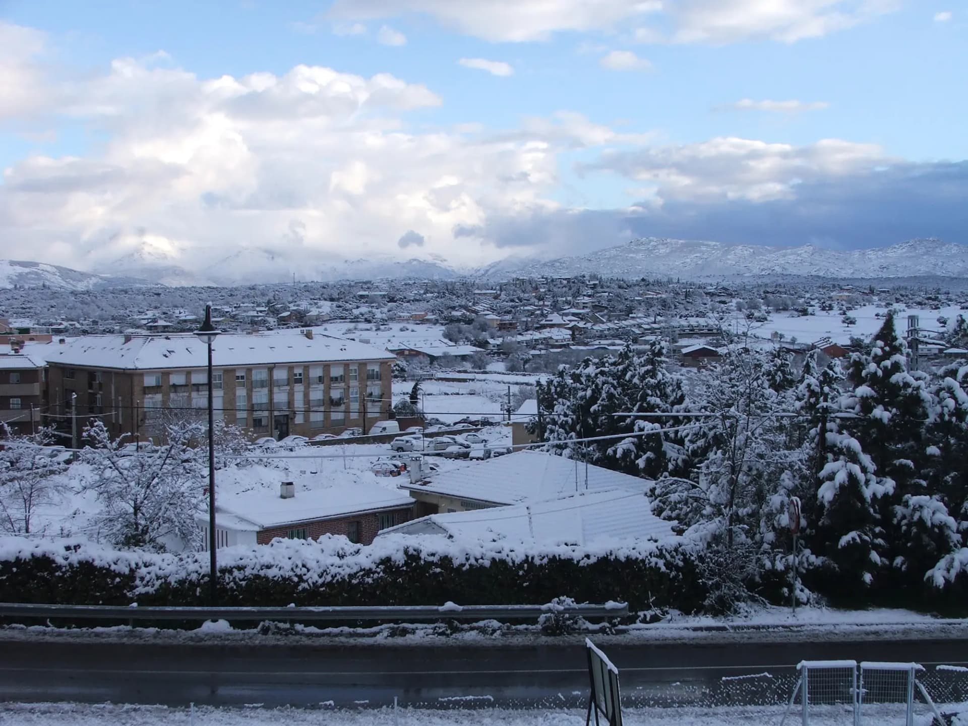 Vista de Galapagar nevado con edificios y la sierra al fondo