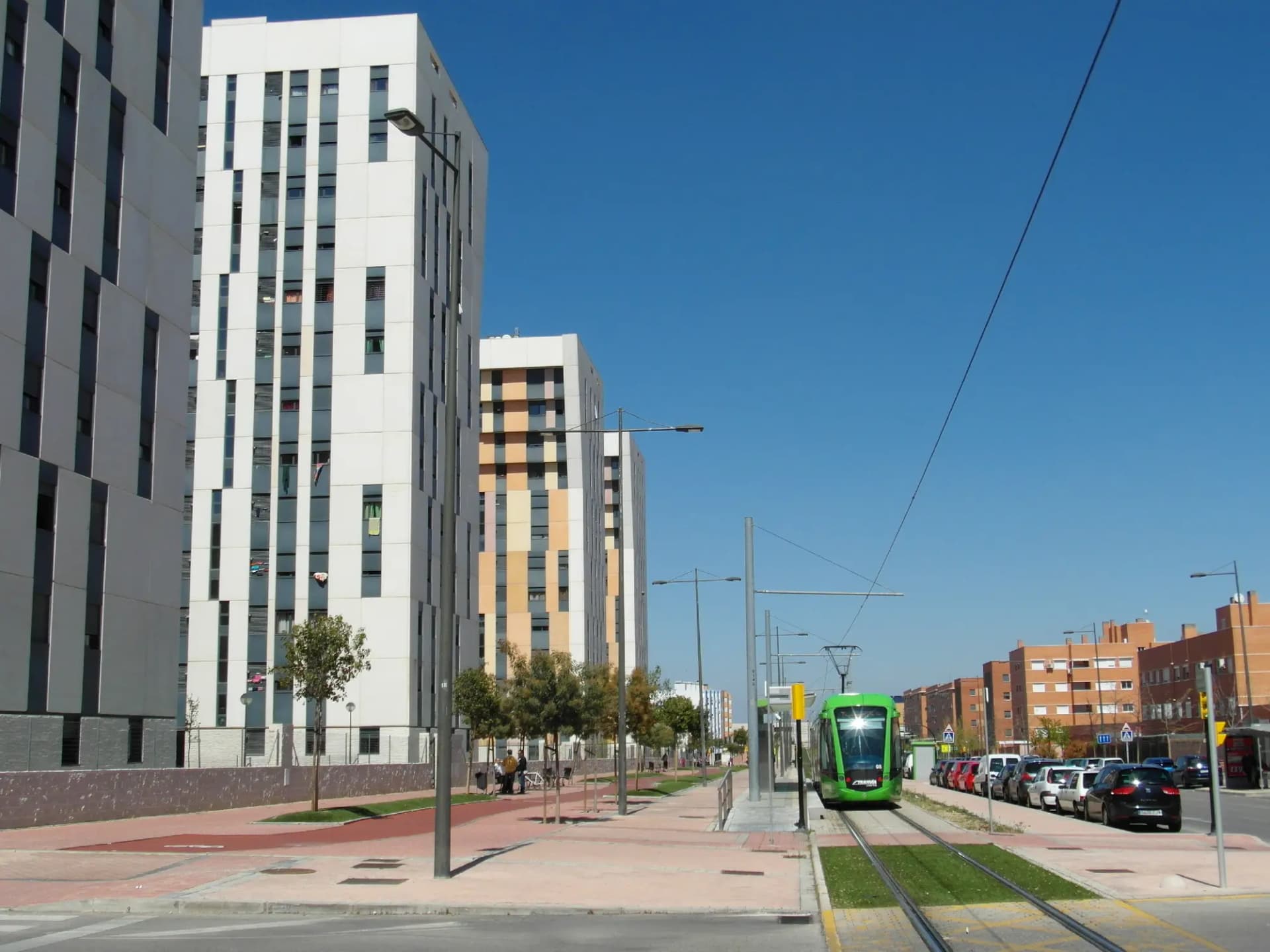 Un tranvía verde circula entre bloques de viviendas nuevas en Parla