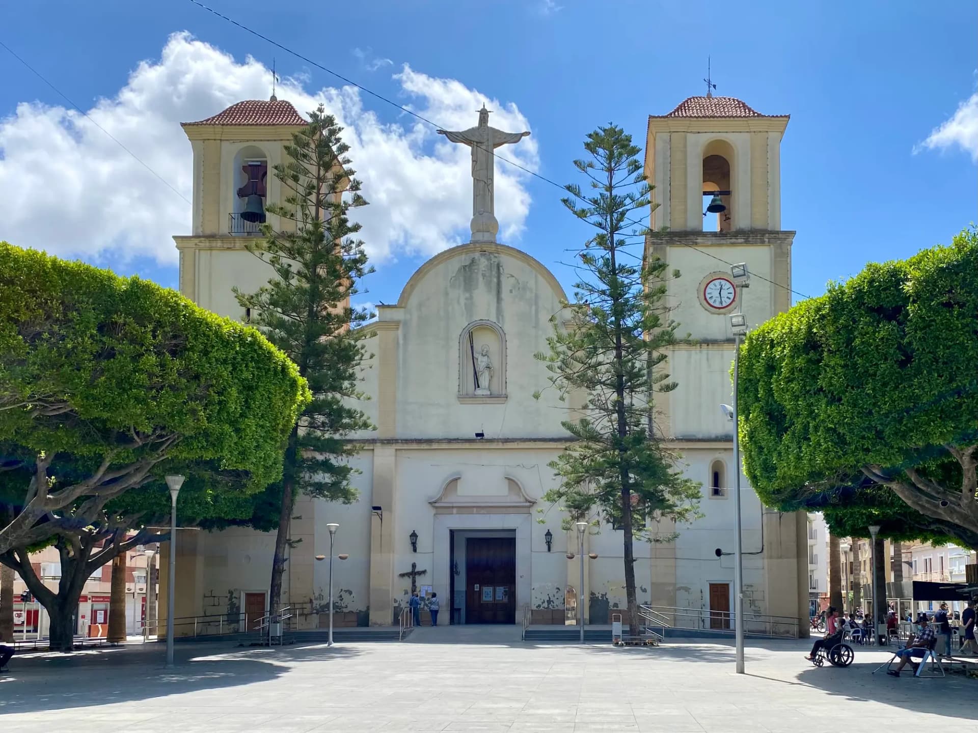 Fachada de la iglesia de San Andrés de Almoradí, con dos torres y la plaza arbolada delante