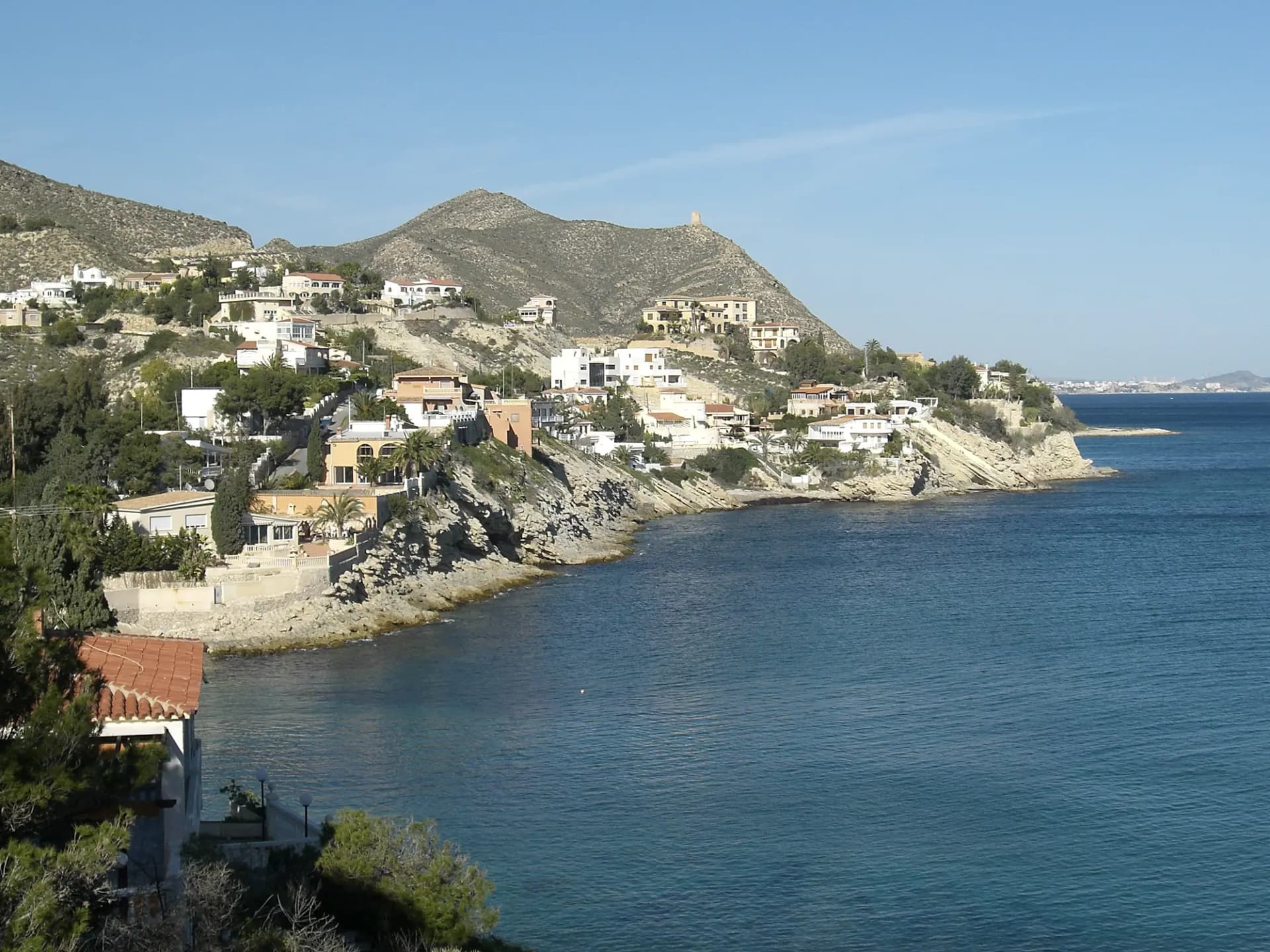 Costa rocosa de El Campello con casas sobre el acantilado y el mar en calma