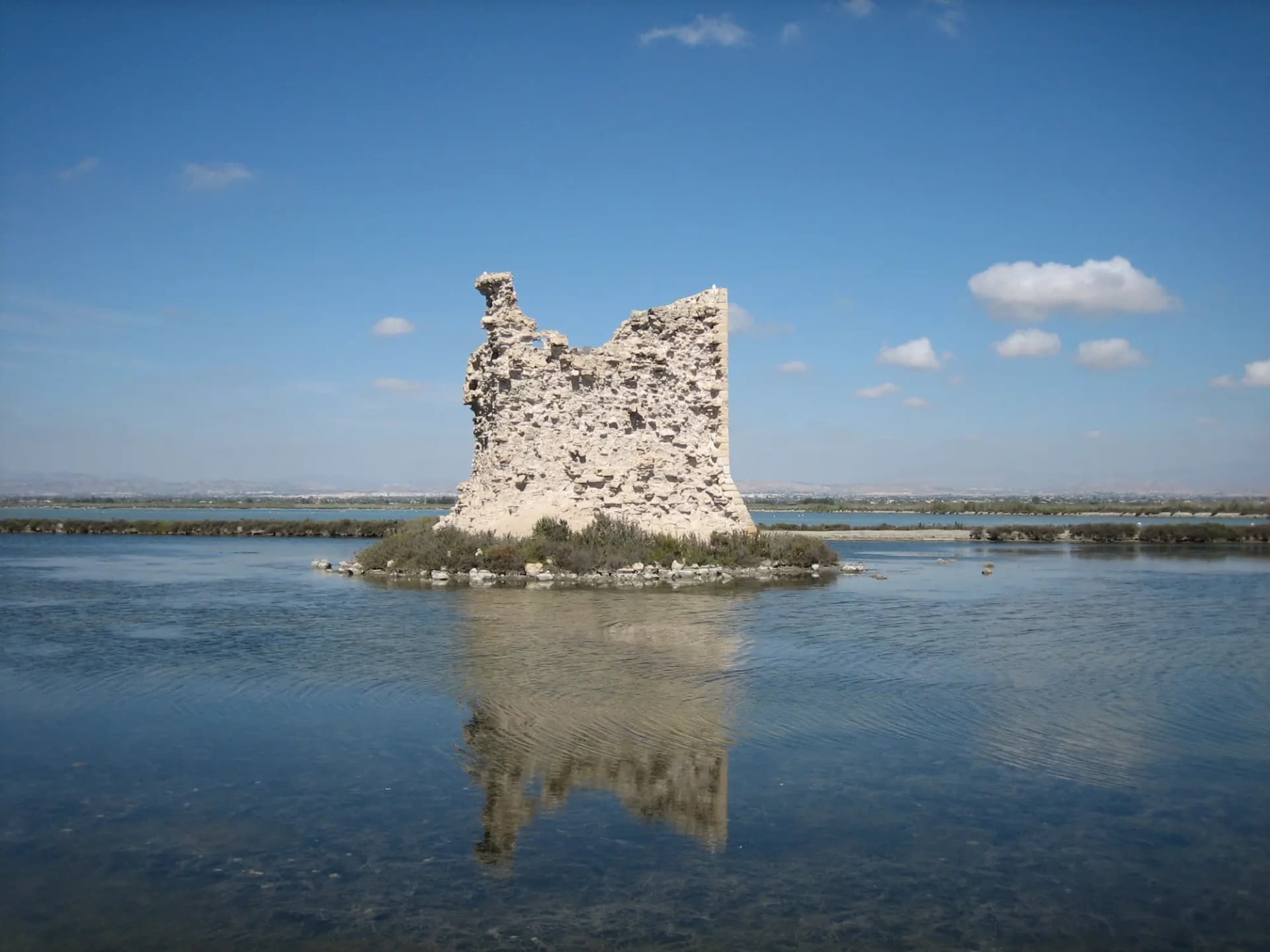 Torre de Tamarit en ruinas reflejada en el agua de las salinas de Santa Pola