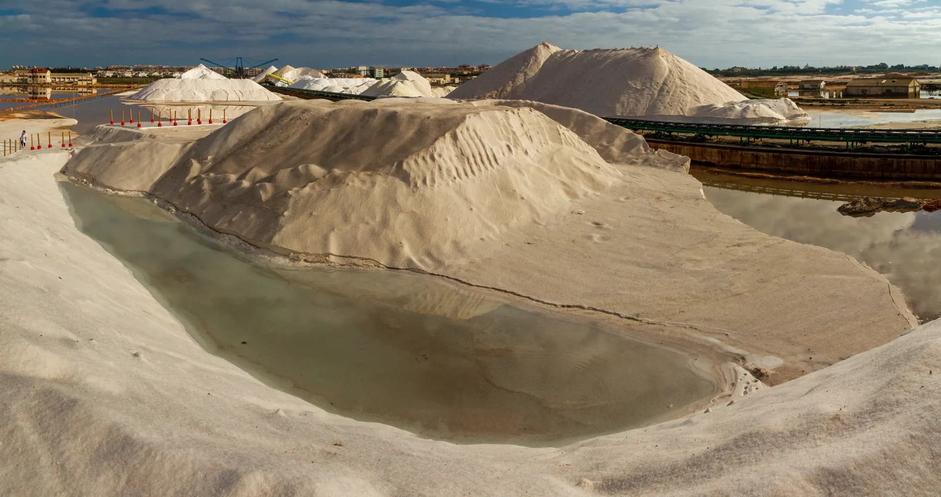 Montañas de sal blanca junto a una balsa de agua en las salinas de la laguna de Torrevieja