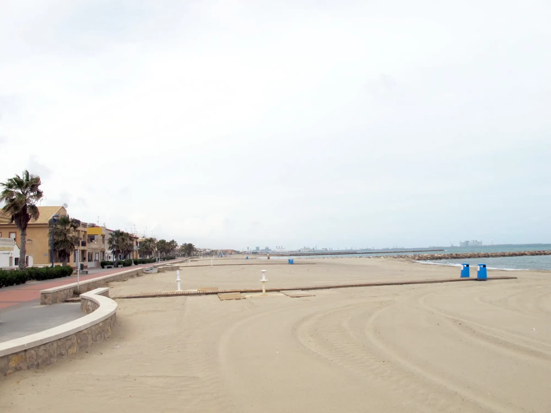 Playa de arena de Puçol con el paseo marítimo y palmeras a la izquierda