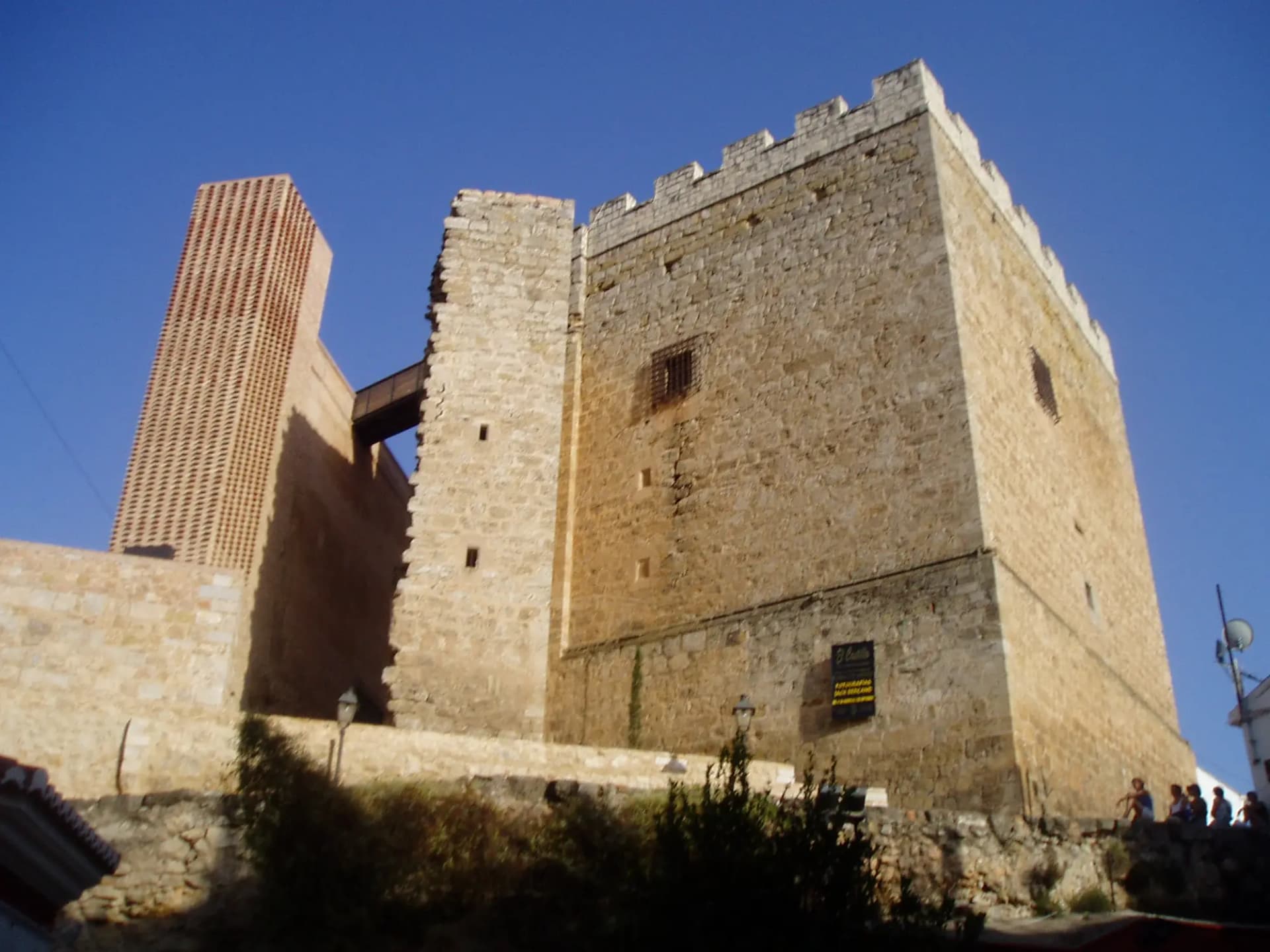 Torre del homenaje del castillo de Requena, de piedra con almenas, bajo un cielo azul