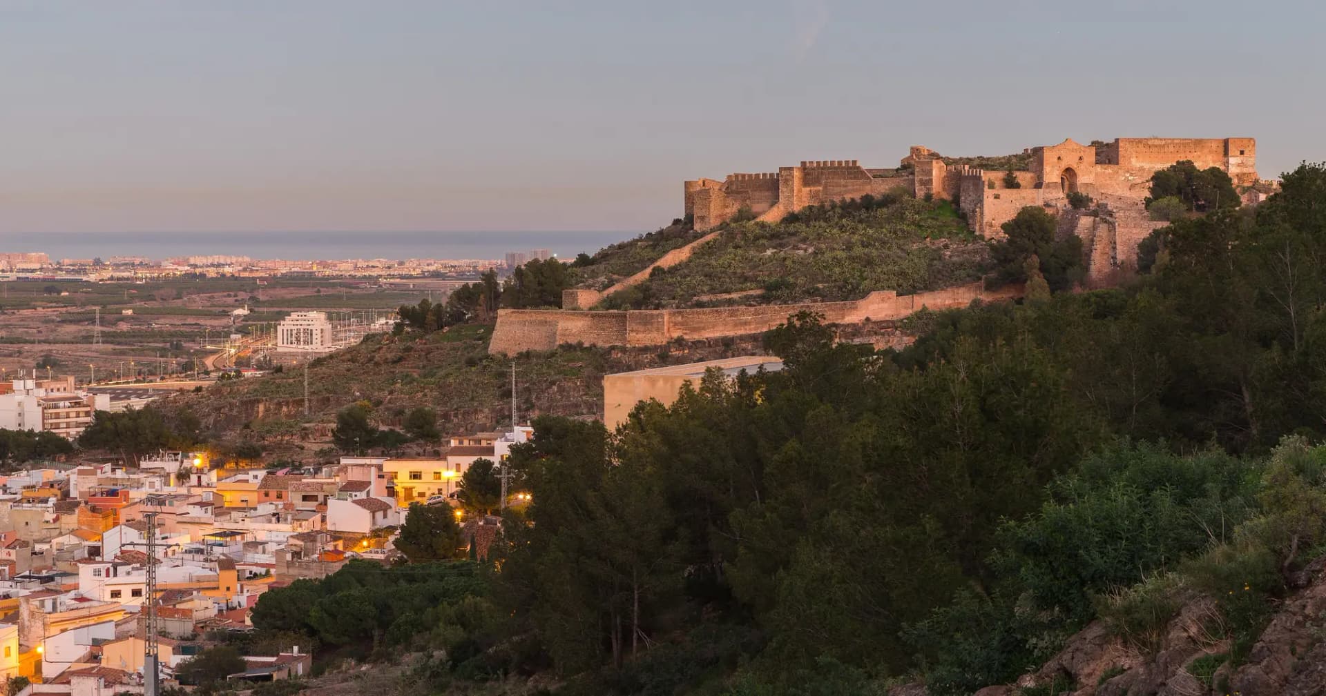 El castillo de Sagunto sobre la ladera, con las casas de la ciudad a sus pies al atardecer