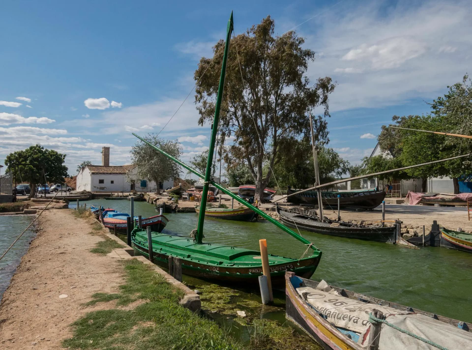 Barcas de la Albufera amarradas en el Port de Silla junto a un camino de tierra