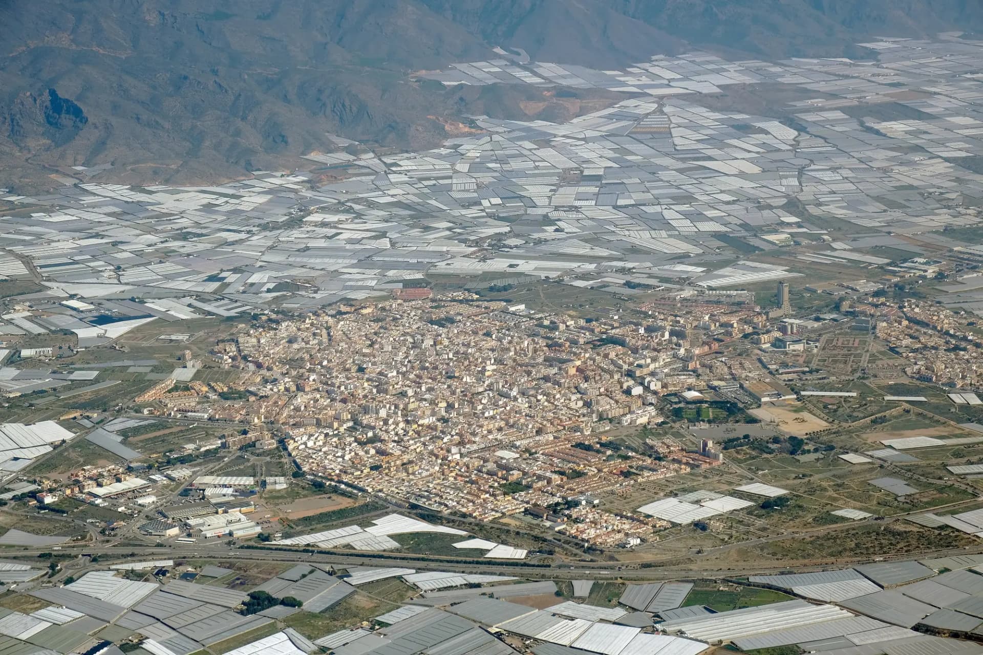 Vista aérea de la ciudad de El Ejido rodeada de invernaderos, con la sierra al fondo