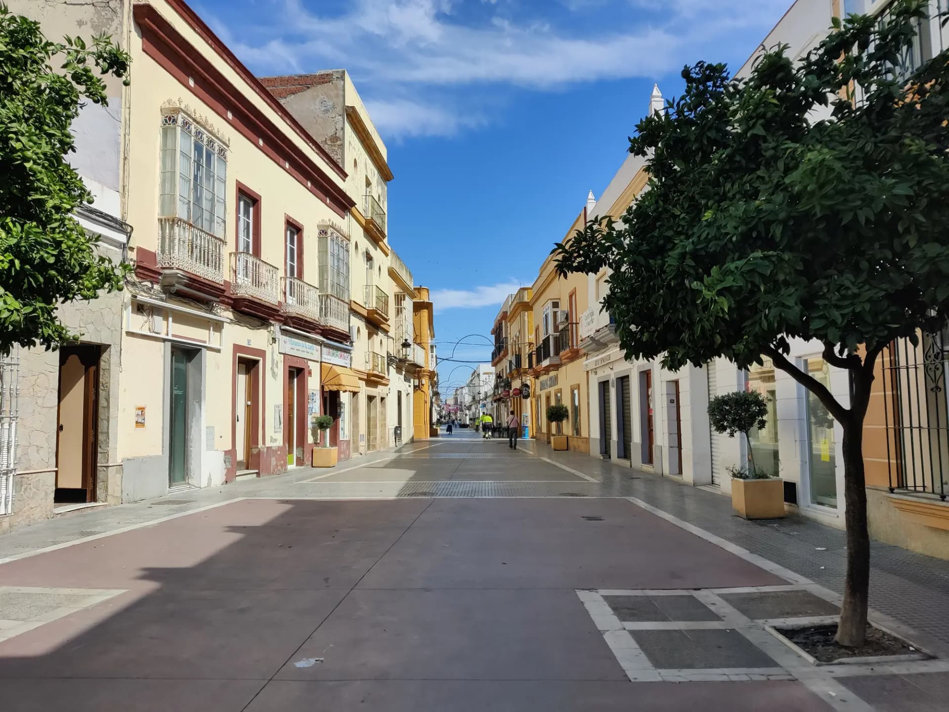 Calle peatonal del centro de Puerto Real con casas encaladas y naranjos
