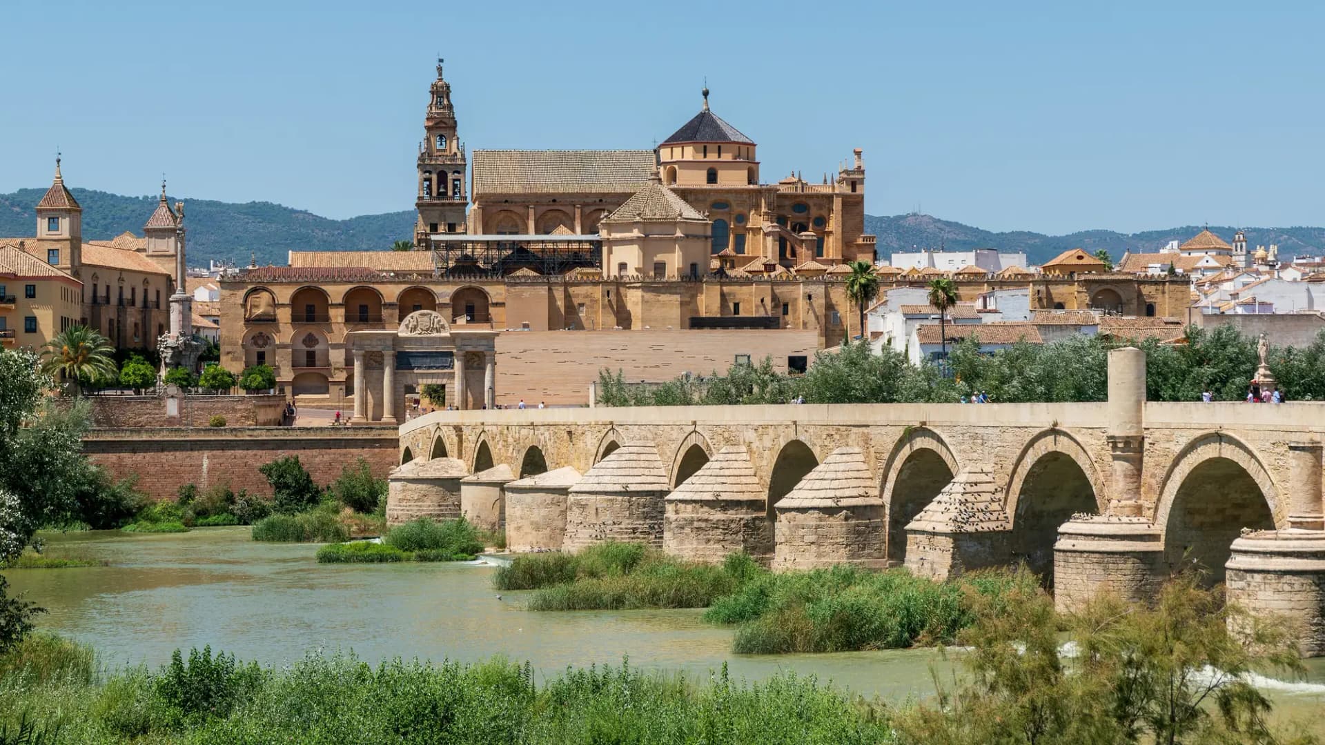 La Mezquita-Catedral de Córdoba sobre el puente romano y el río Guadalquivir en un día soleado