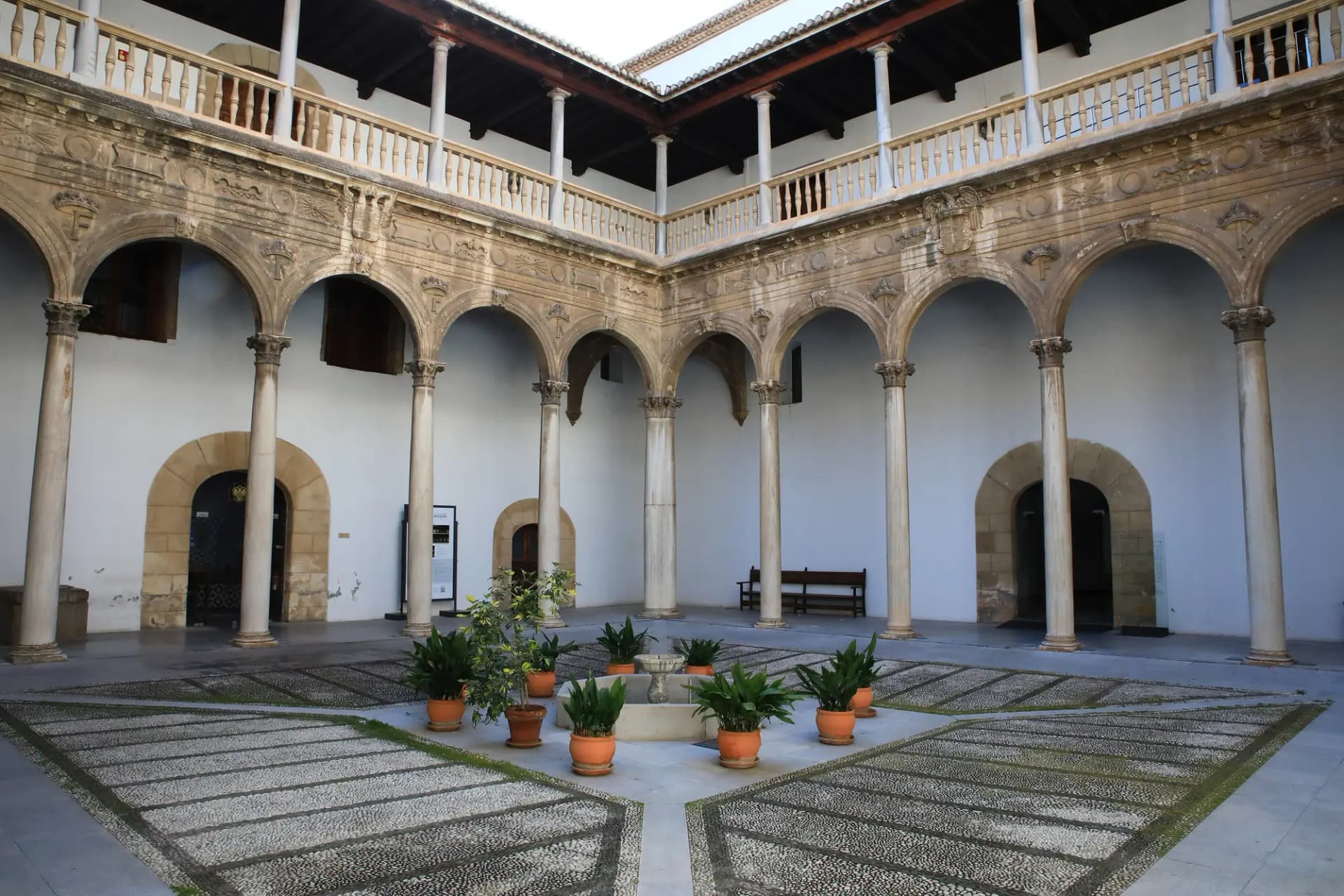 Patio renacentista de dos alturas con arcos y columnas en el Hospital Real de Granada