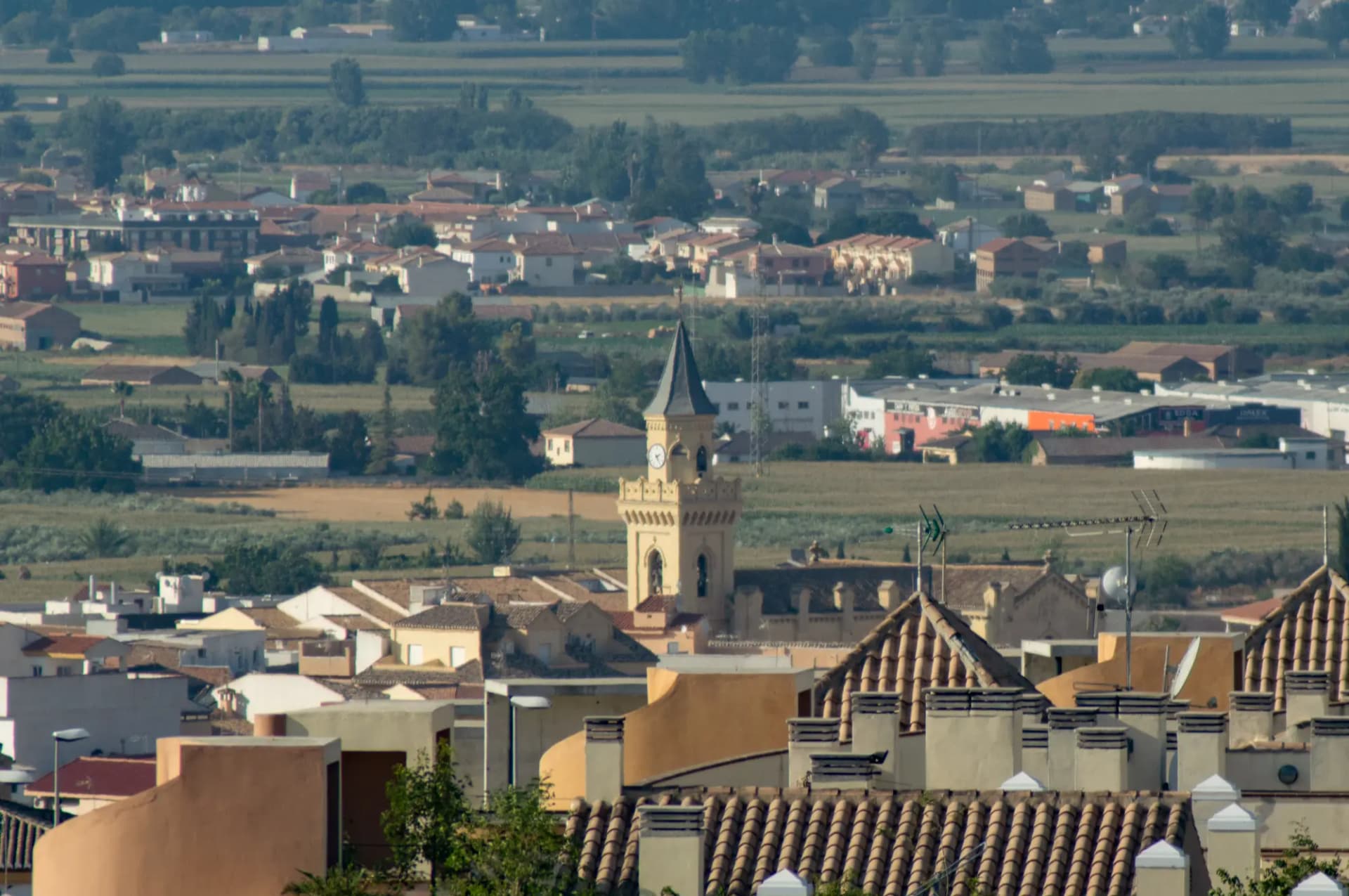 Torre de la iglesia de Las Gabias entre tejados con la vega al fondo