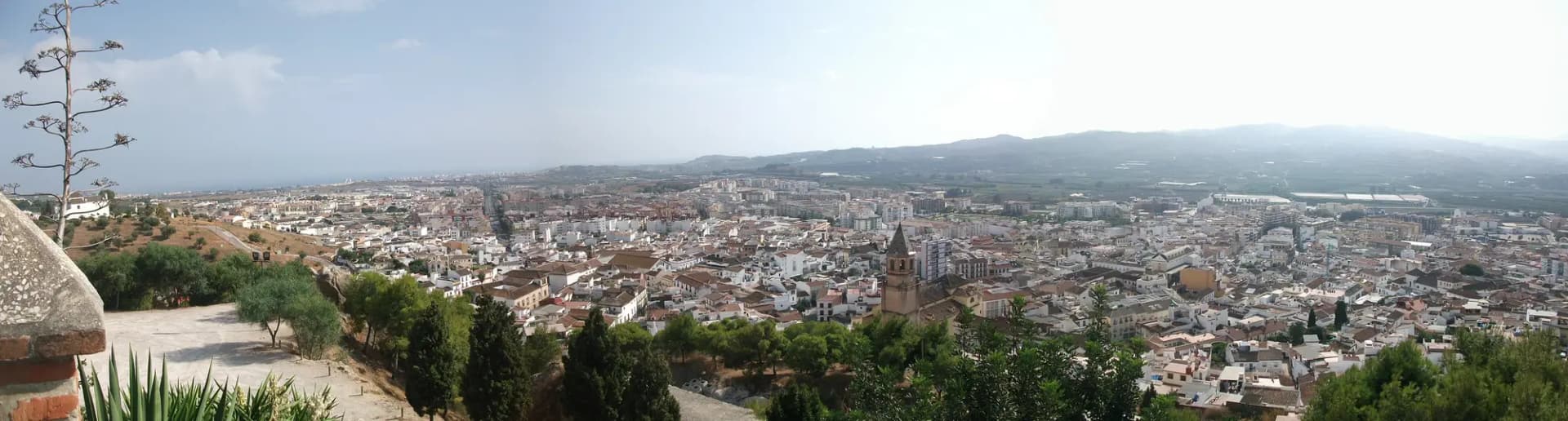 Panorámica de Vélez-Málaga desde la fortaleza, con la ciudad blanca, la torre de una iglesia y la vega hasta las montañas
