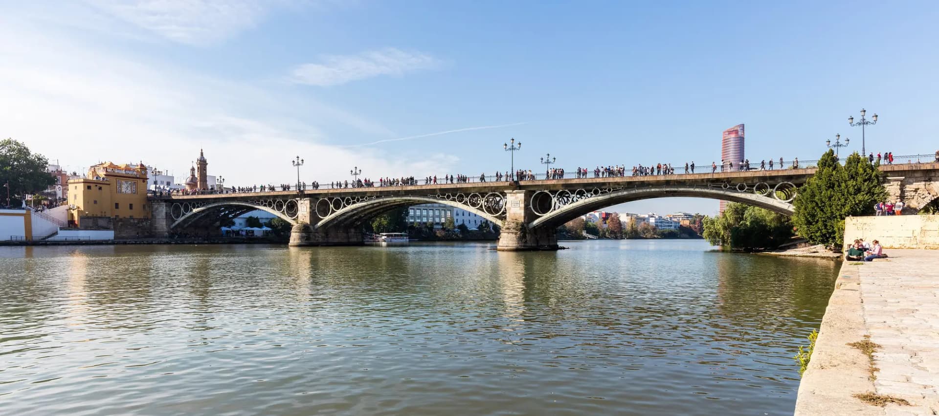 El puente de Triana sobre el Guadalquivir con el barrio de Triana a la izquierda y el cielo despejado