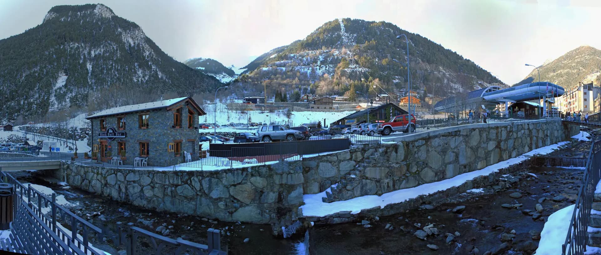 Panorámica de Arinsal en invierno, con el río, casas de piedra, la estación del telecabina y montañas nevadas