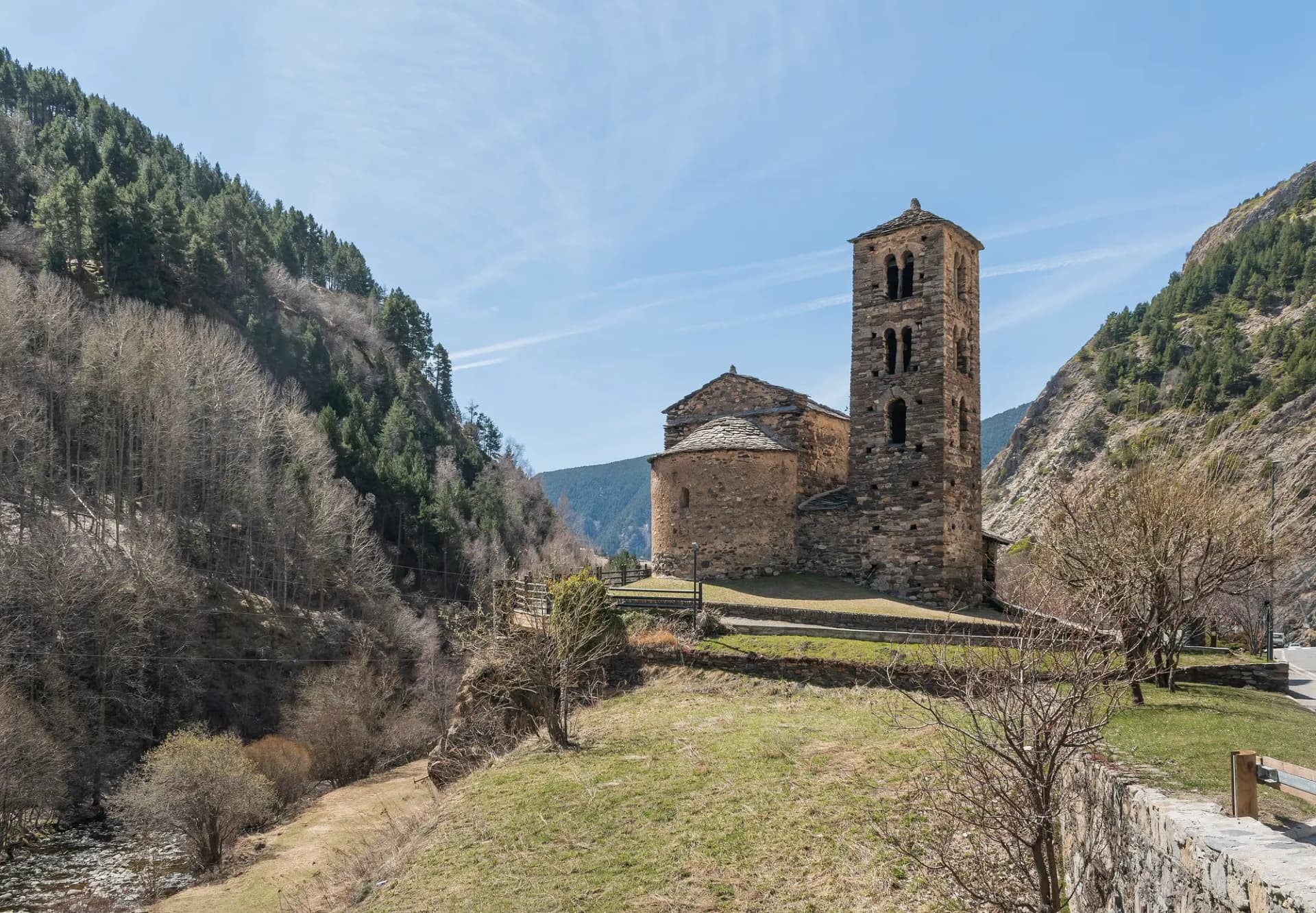 Iglesia románica de Sant Joan de Caselles, con su campanario de piedra, entre laderas de bosque
