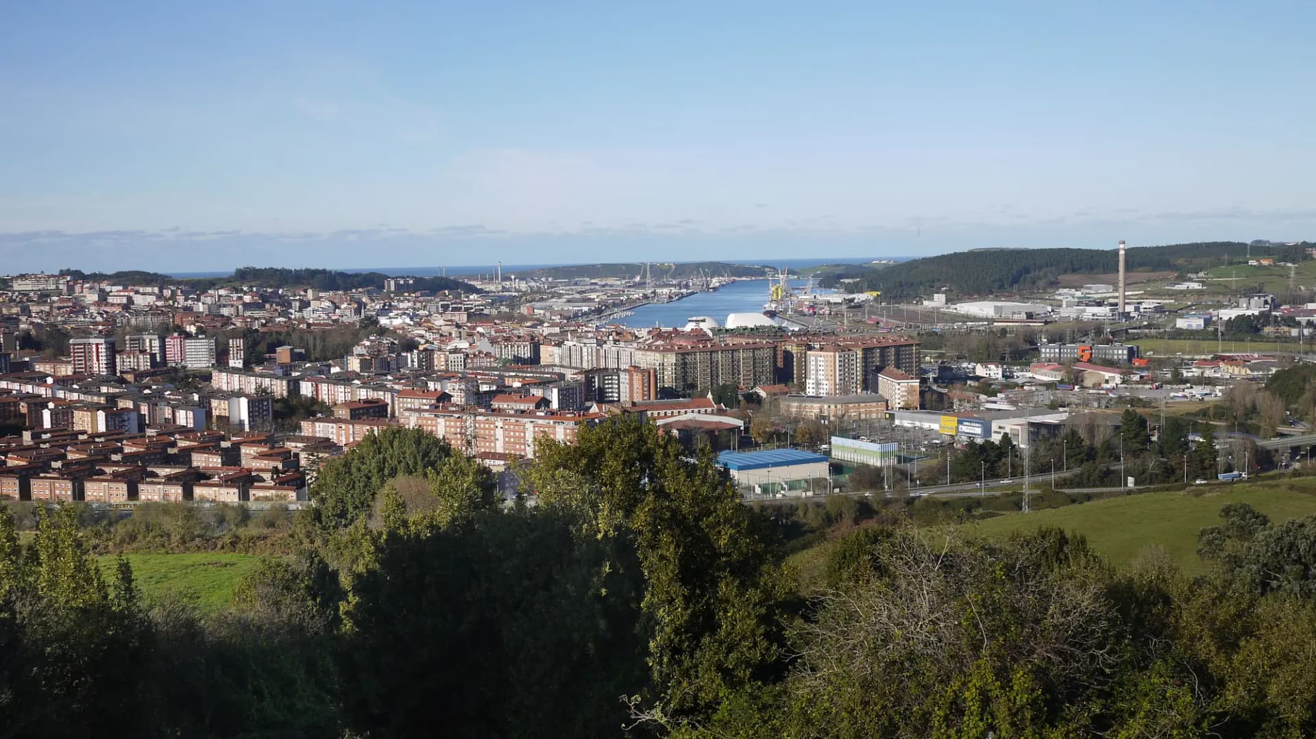 Panorámica de Avilés desde el barrio de La Luz, con los edificios de la ciudad, la ría y las instalaciones industriales al fondo