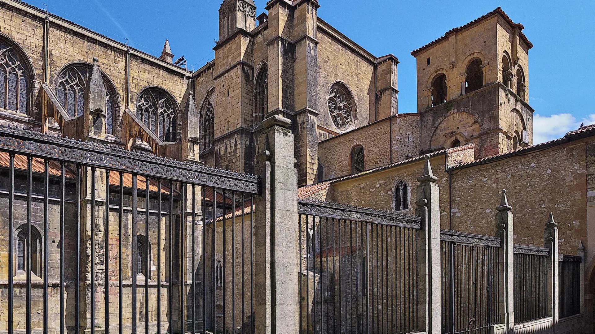 Fachada lateral y torres de la Catedral de San Salvador de Oviedo detrás de una verja de hierro