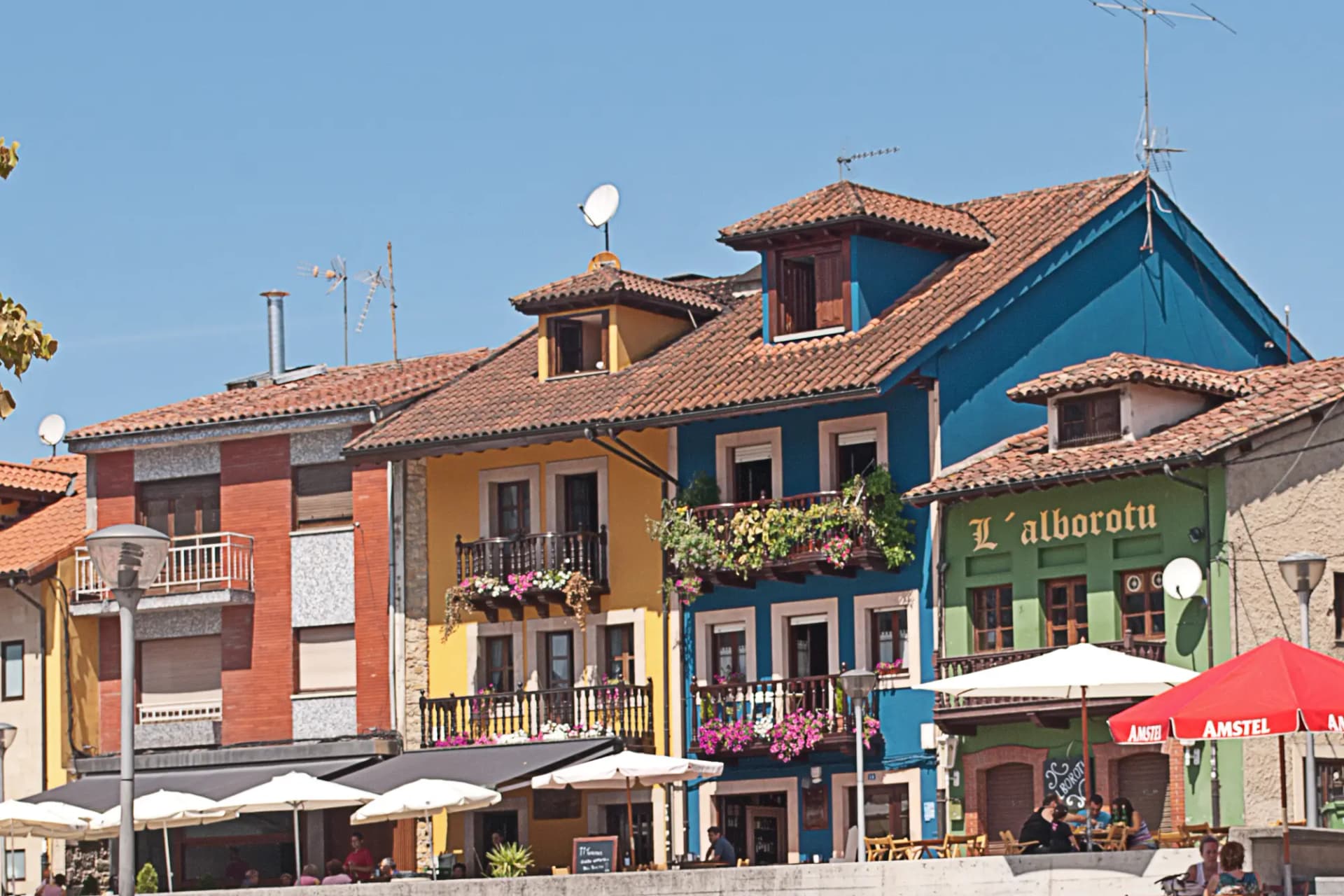 Casas de colores con balcones y terrazas de hostelería en una plaza de La Pola Siero