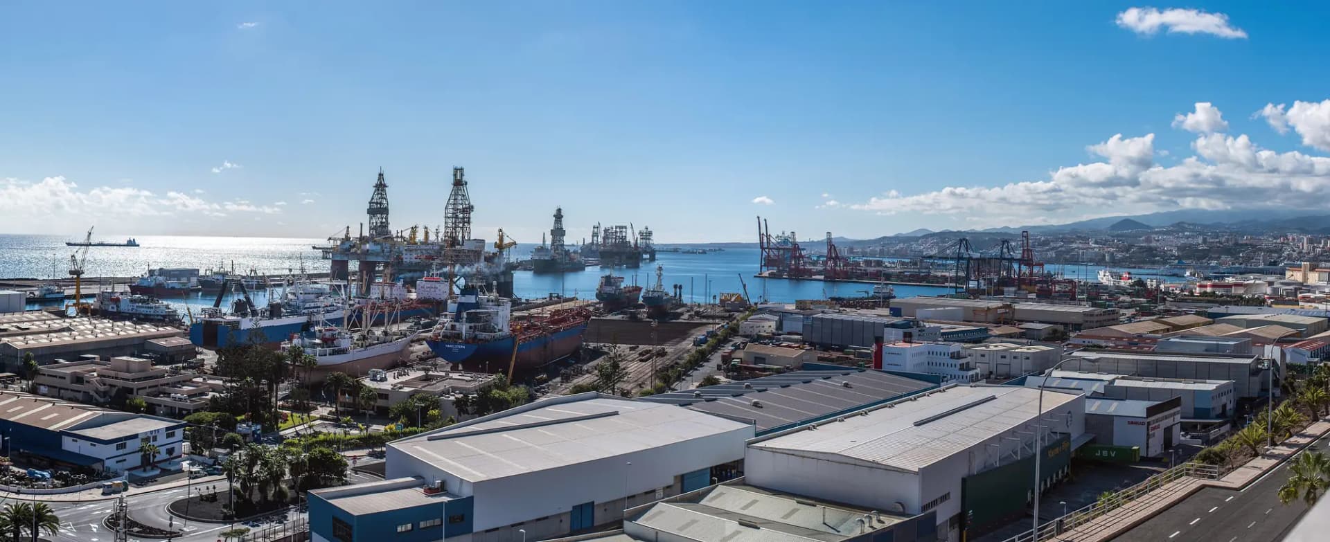 Vista del Puerto de la Luz con naves industriales en primer plano y plataformas petrolíferas atracadas al fondo