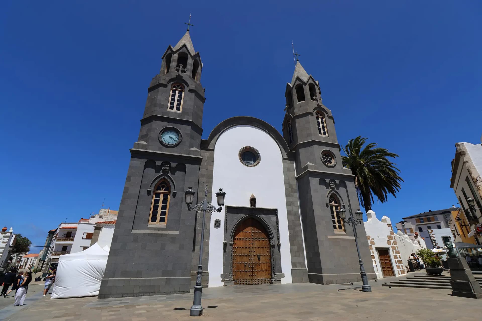 Fachada blanca y de piedra oscura de la basílica de San Juan Bautista, con dos torres neogóticas