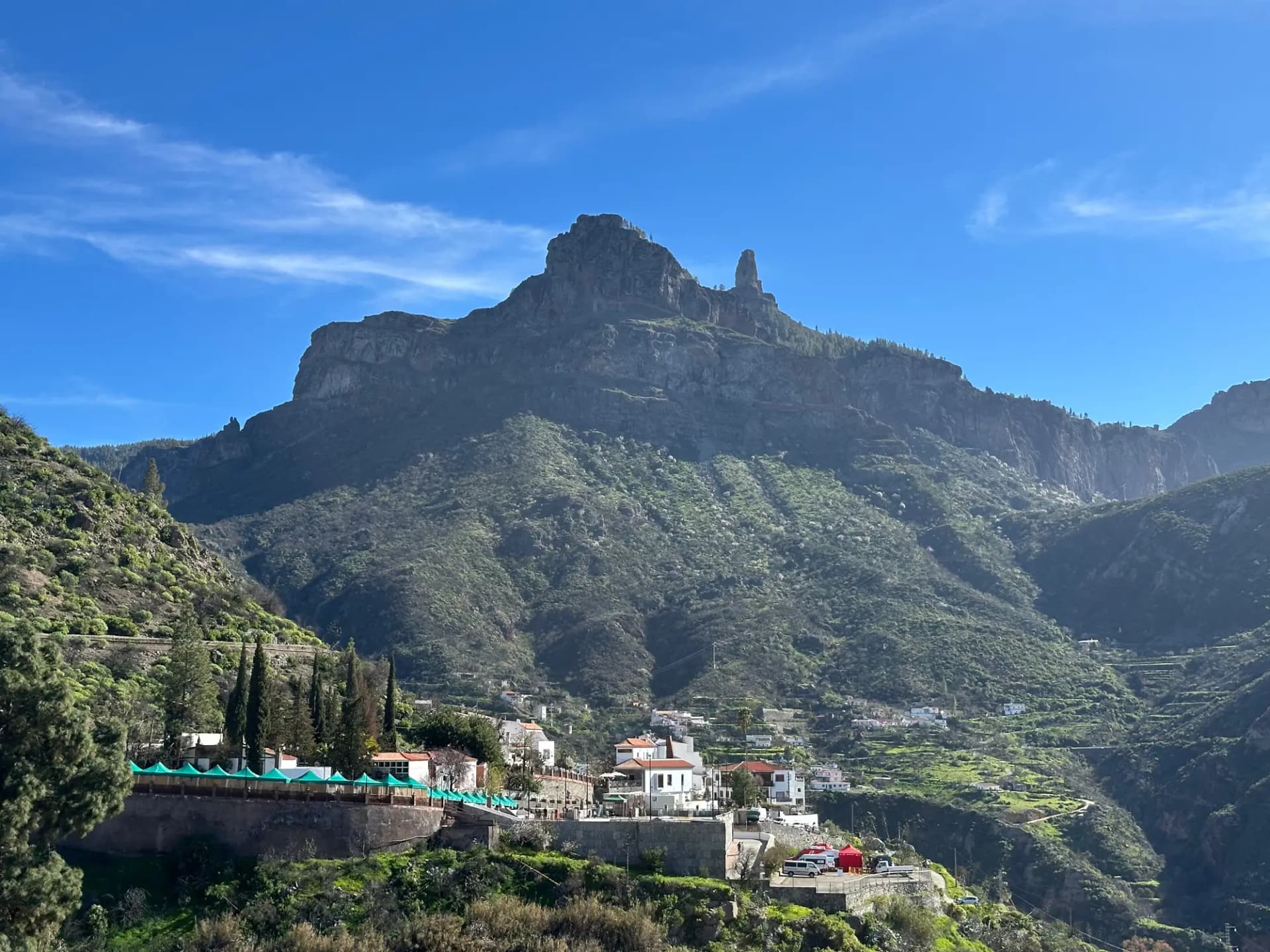 El Roque Nublo sobre las montañas verdes de Tejeda, con casas blancas en primer plano