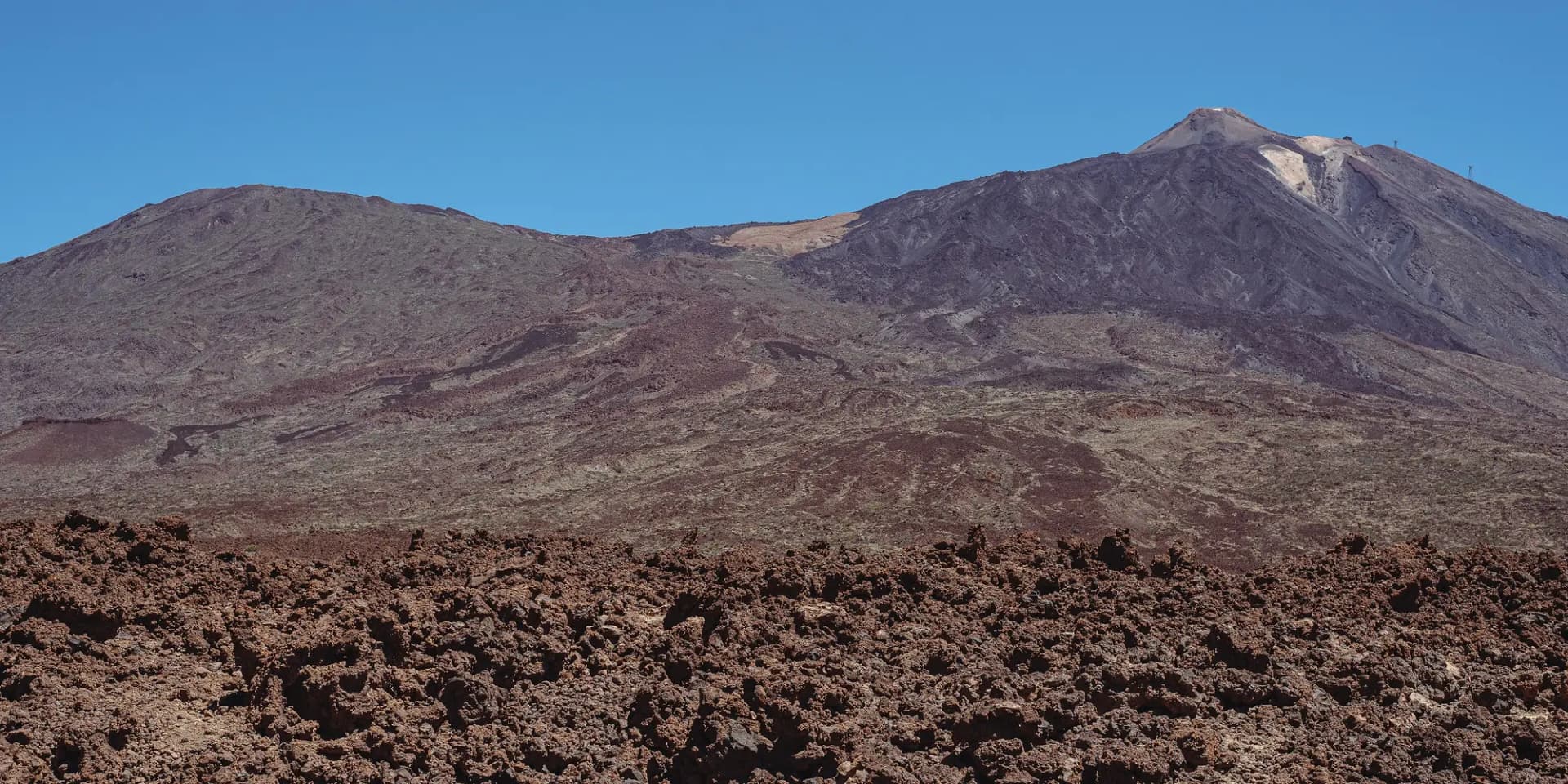 La cumbre del Teide sobre un campo de lava rojiza en el Parque Nacional del Teide