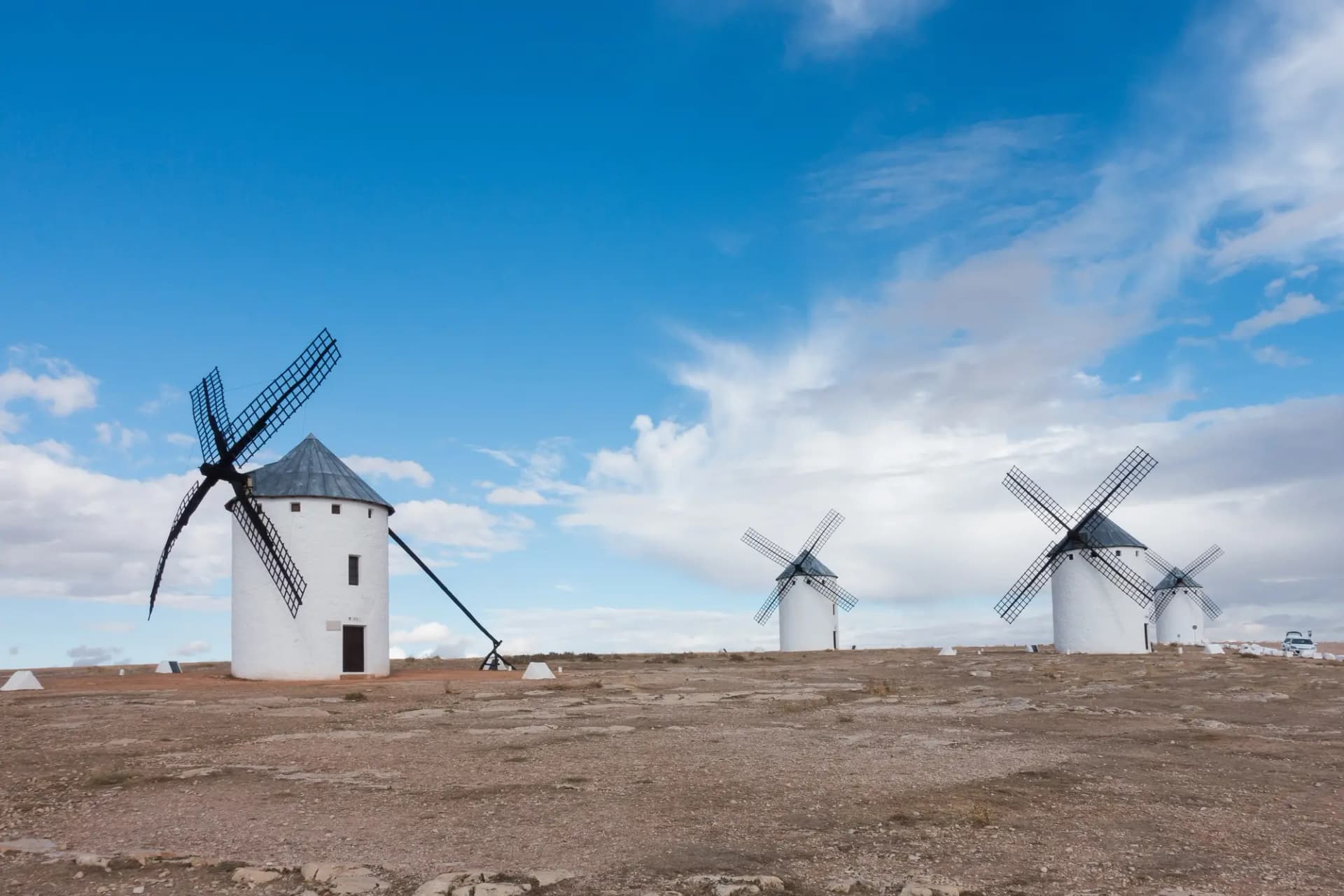 Molinos de viento blancos en lo alto de la sierra bajo un cielo azul con nubes