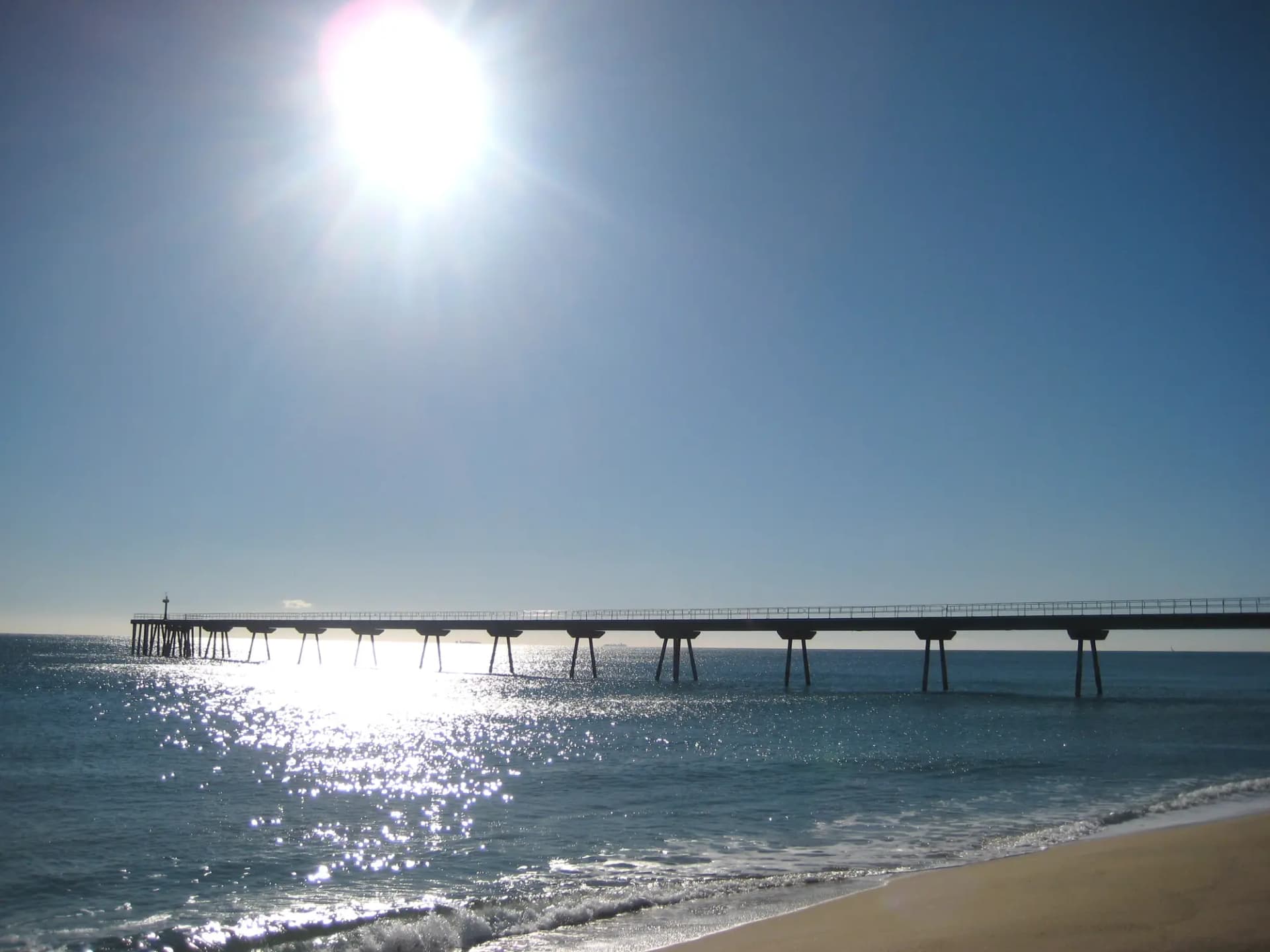 El Pont del Petroli de Badalona adentrándose en el mar, a contraluz
