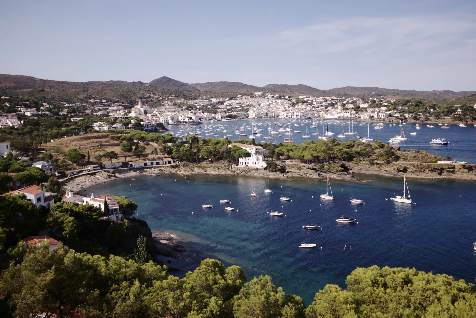 La bahía de Cadaqués con veleros fondeados y el pueblo blanco al fondo