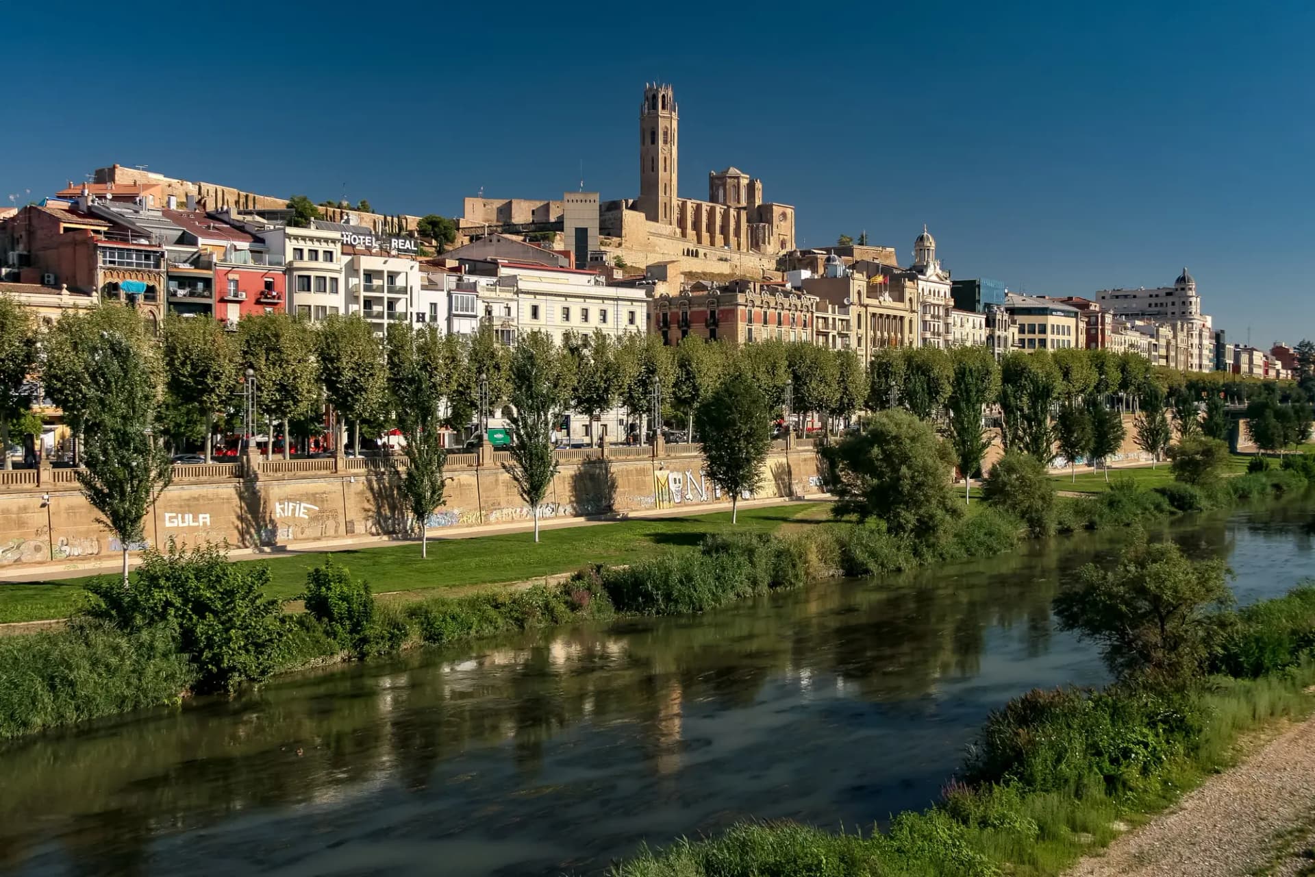 La Seu Vella sobre la ciudad de Lleida, con el río Segre y su paseo arbolado en primer plano