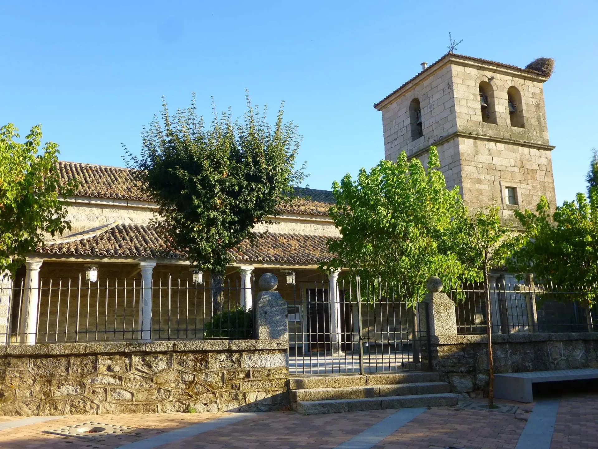 Iglesia de Nuestra Señora del Enebral, de granito, con su torre y su pórtico, en el casco de Collado Villalba
