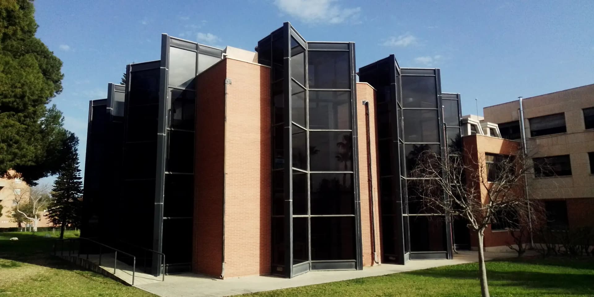 Edificio de ladrillo y cristal de la Biblioteca de Derecho en el campus de la Universidad de Alicante