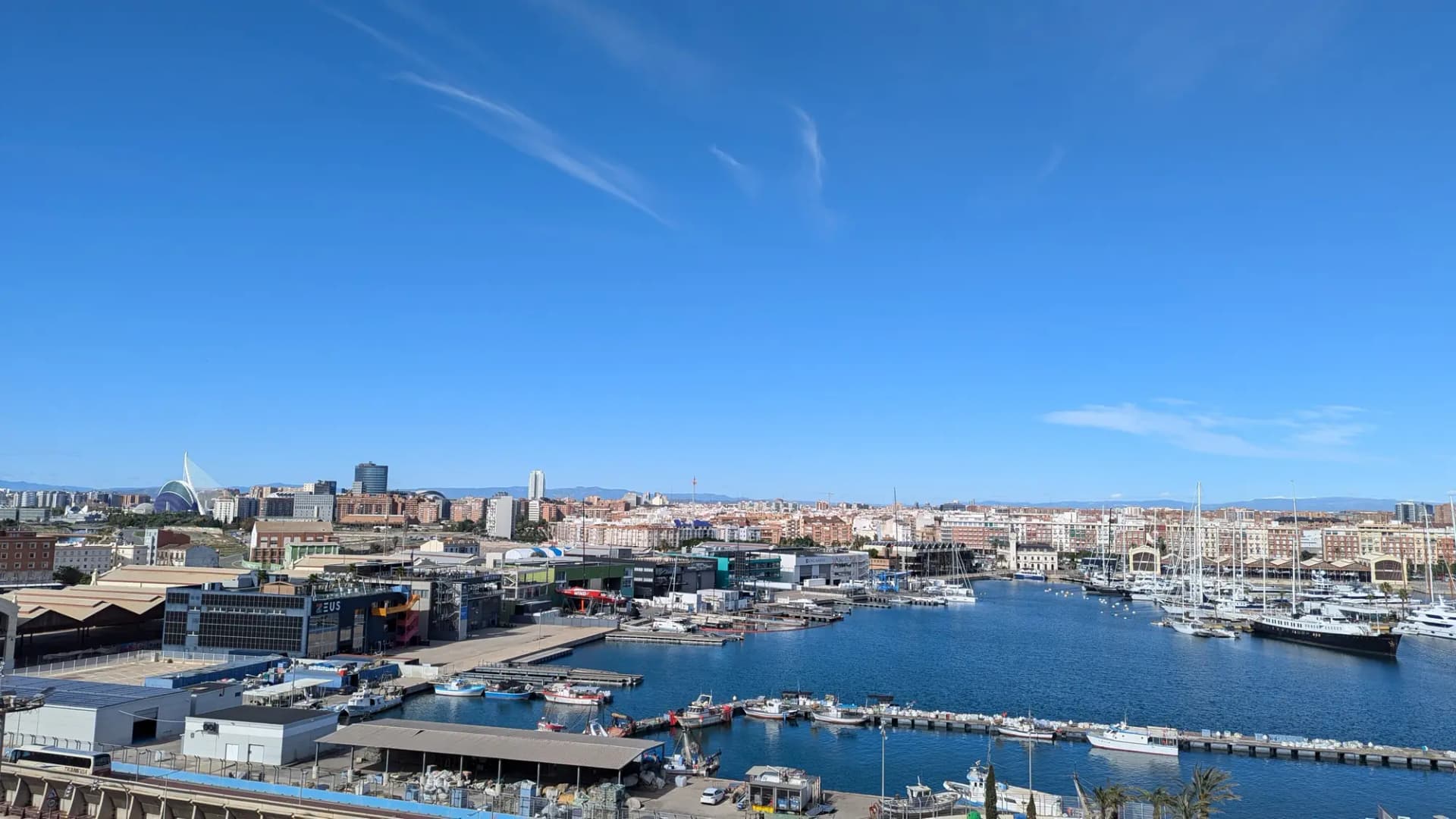 Vista de València desde el puerto, con la dársena y los barcos en primer plano y la ciudad al fondo