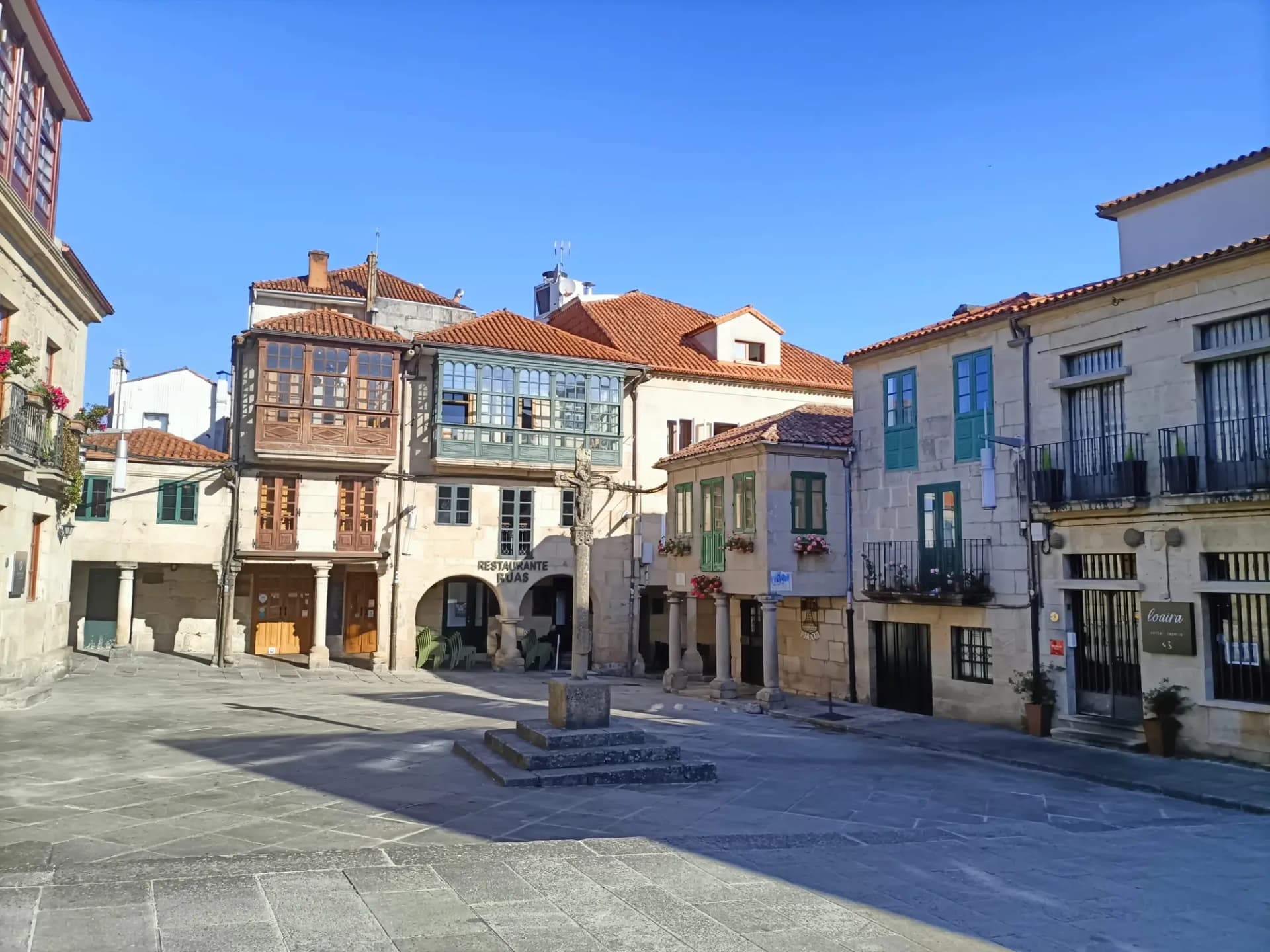 Casas de piedra con galerías y balcones alrededor del cruceiro de la Praza da Leña