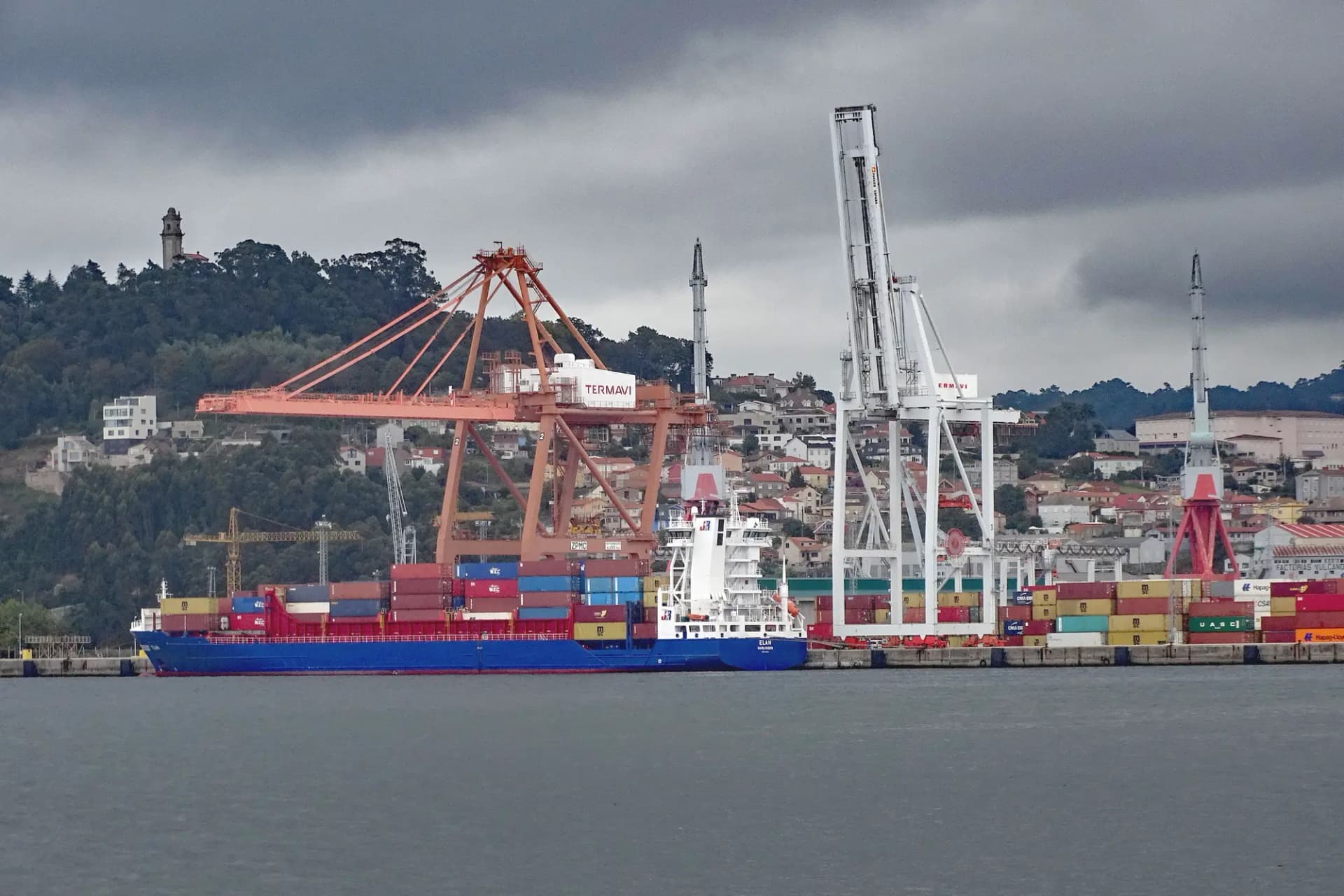 Portacontenedores atracado bajo las grúas de la terminal del puerto de Vigo, con la ciudad en la ladera